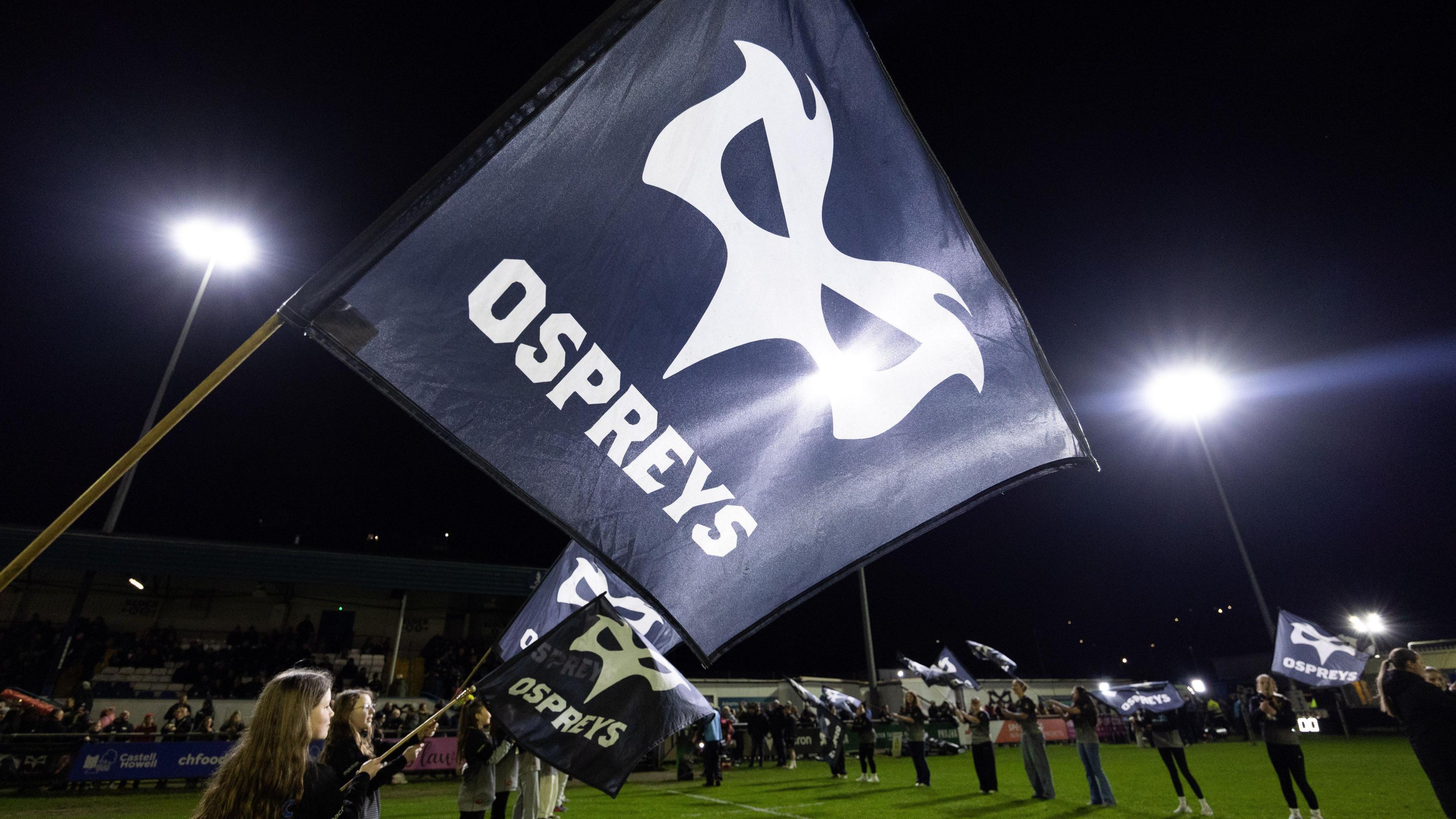 Mascots wave Ospreys flags in a tunnel to welcome the teams onto the pitch at Bridgend's Brewery Field