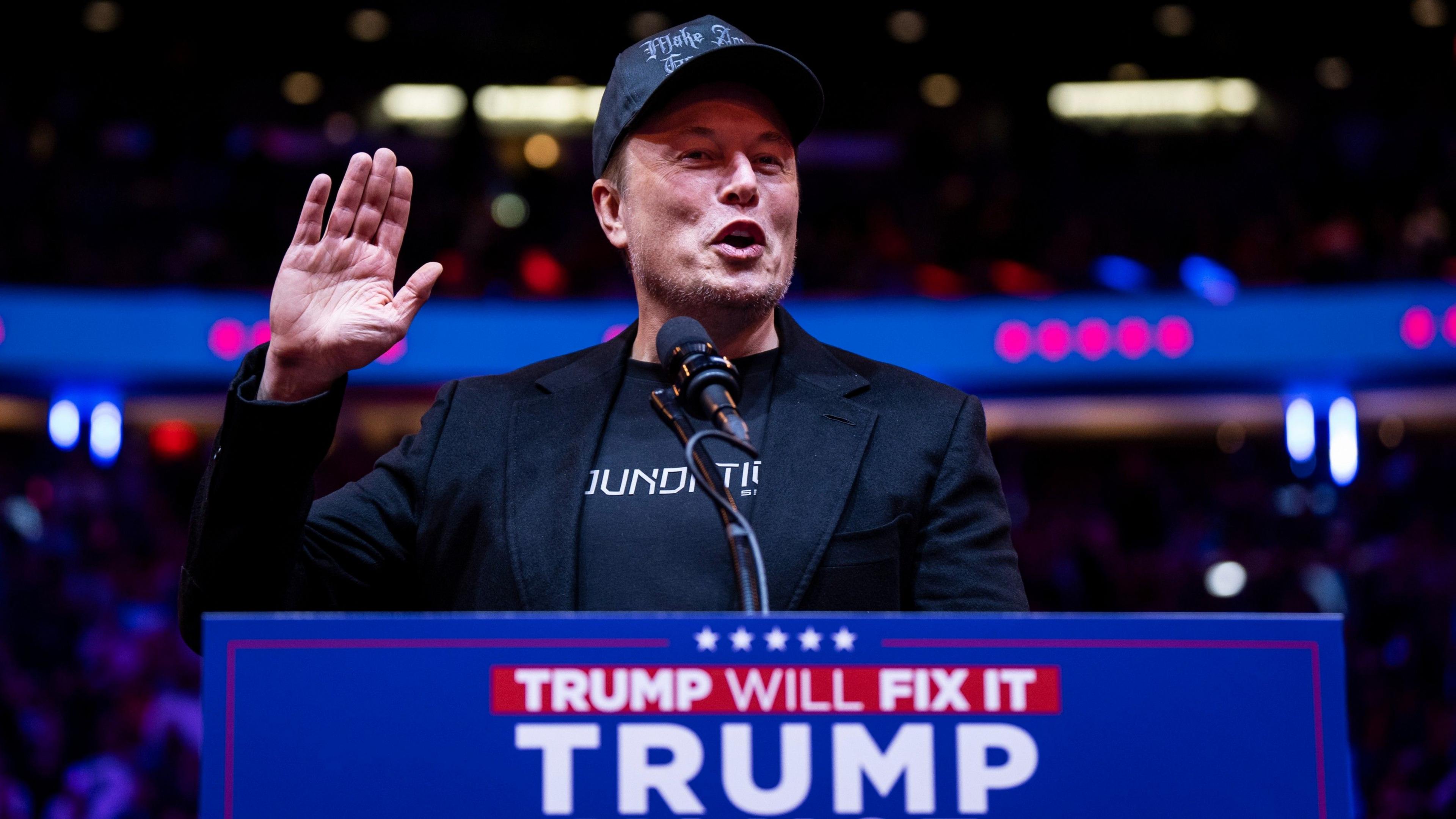 Elon Musk in front of Trump sign