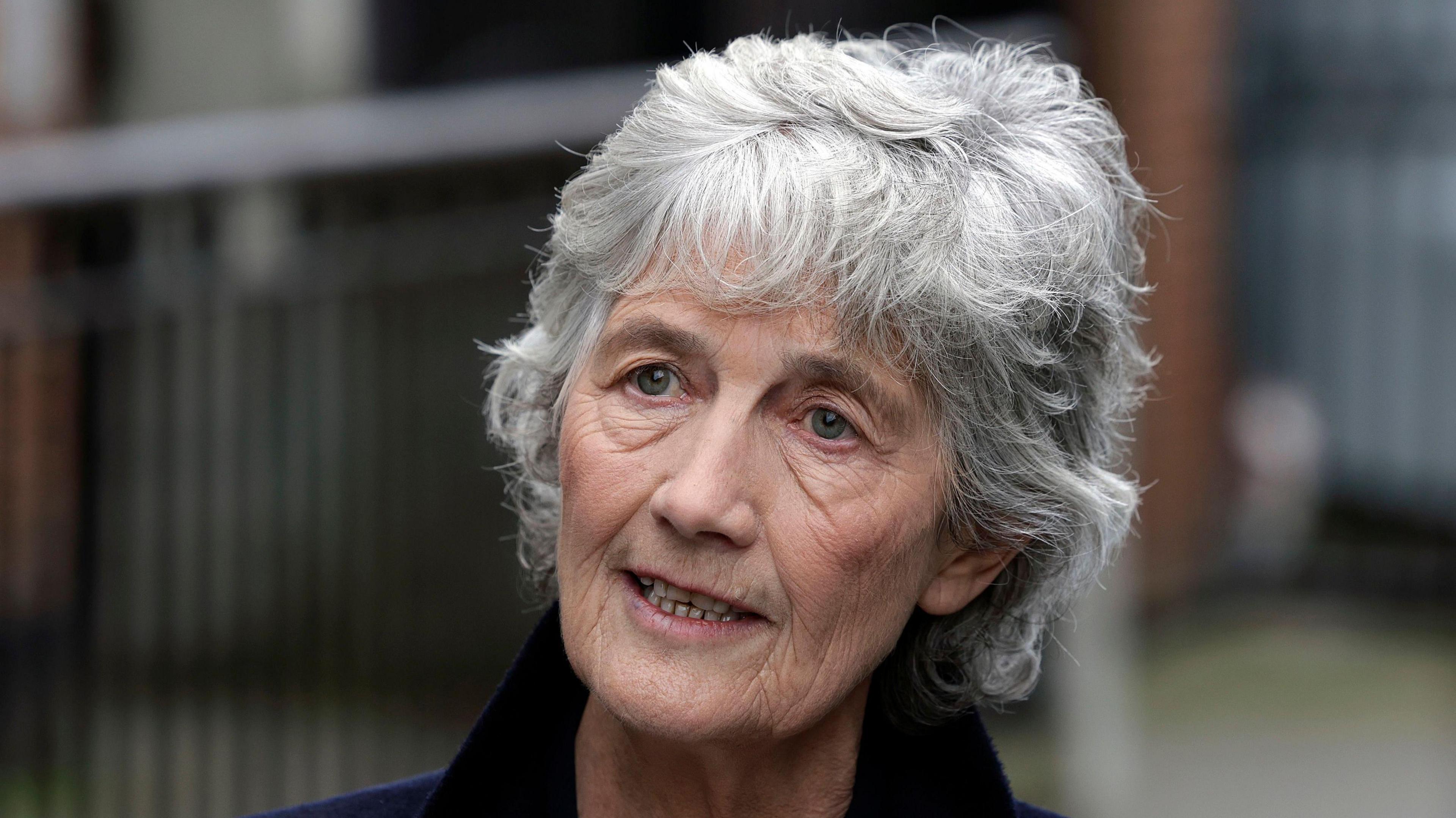Catherine Connolly, an older woman with short grey hair, pictured from the shoulders up. The background of the image is blurred.