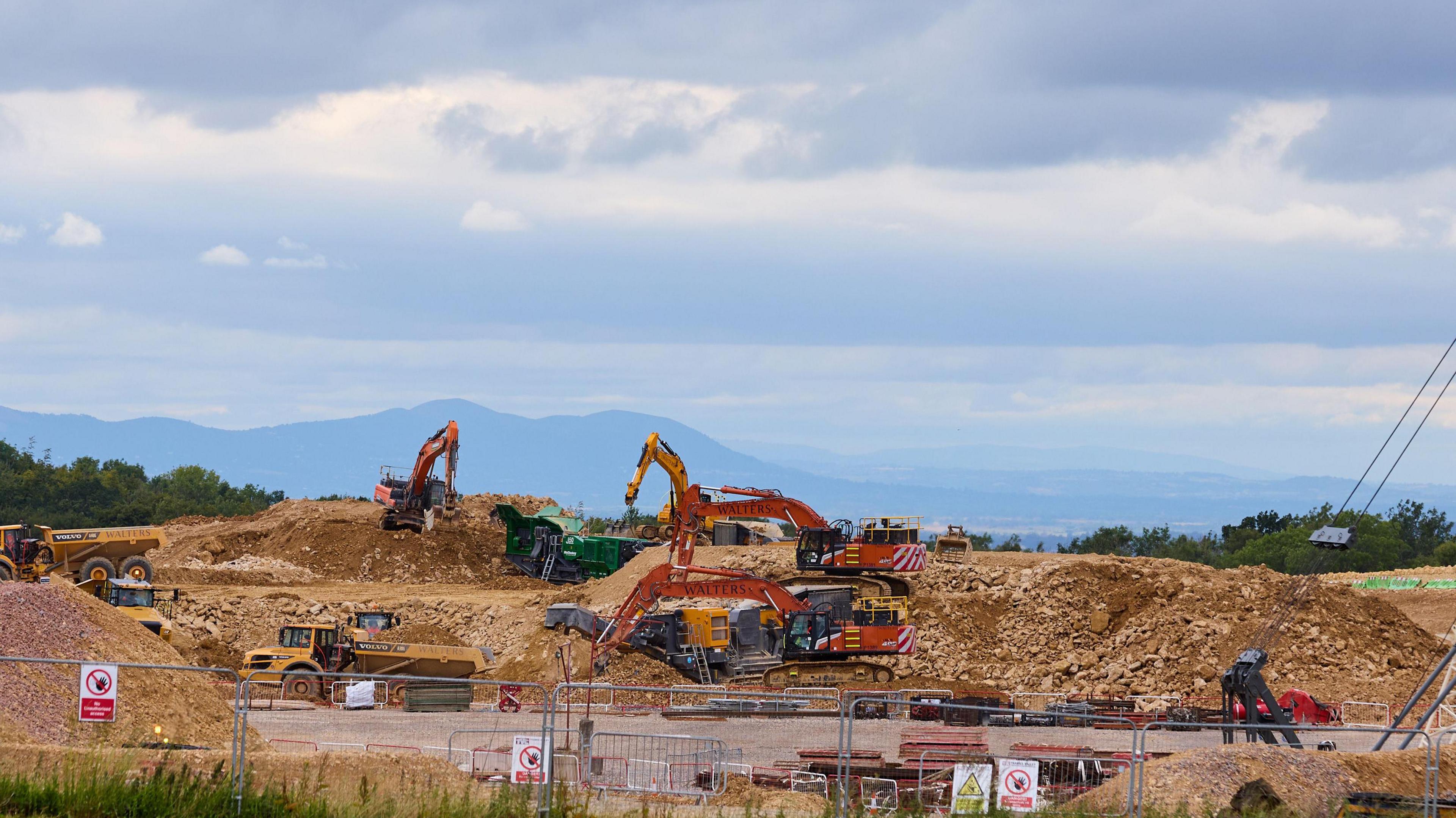 Shab Hill, looking towards Stockwell. Gravel is piled up on the sides and there are three red cranes.