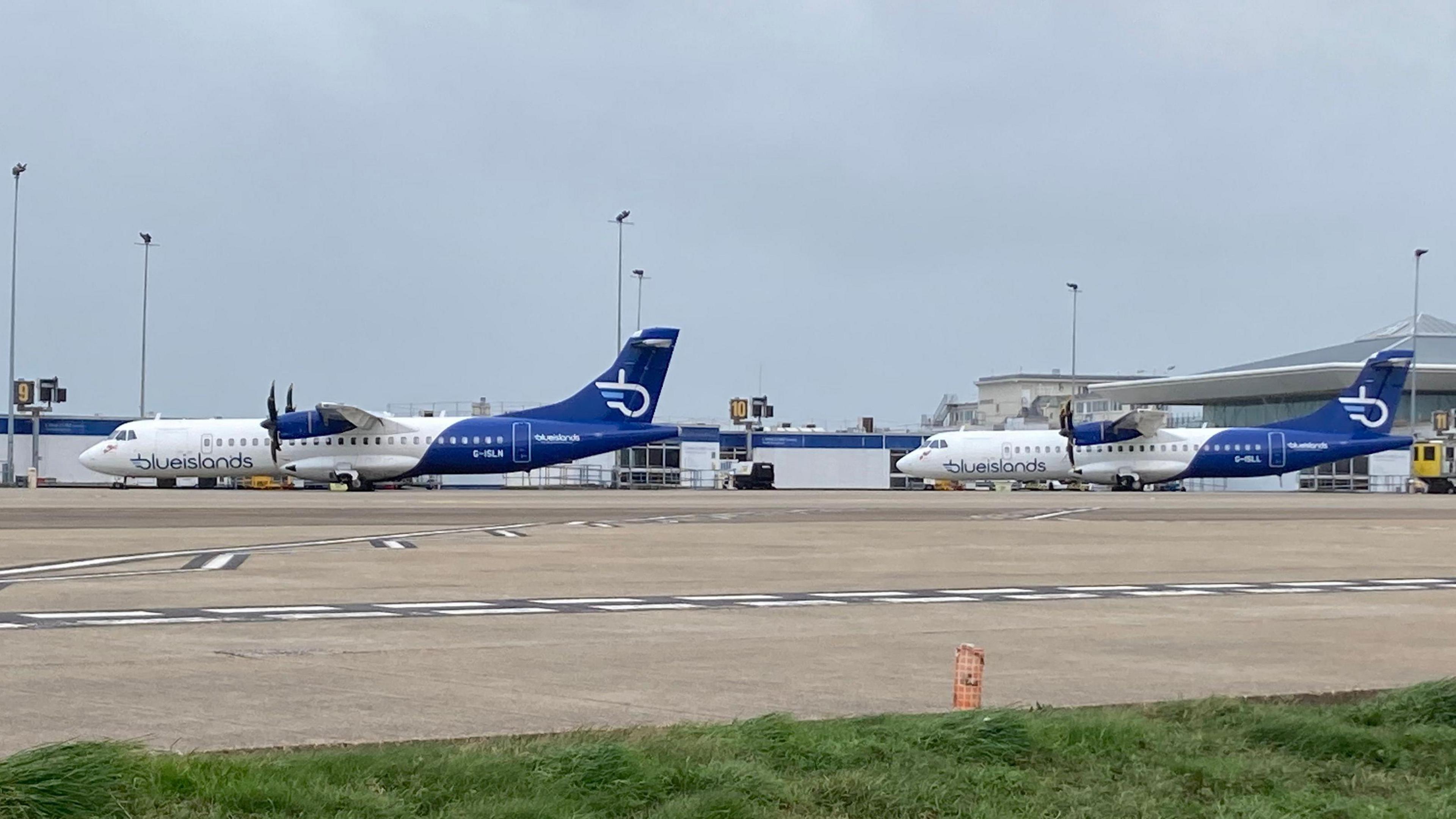 Two Blue Islands planes at Jersey Airport with the terminal building behind.