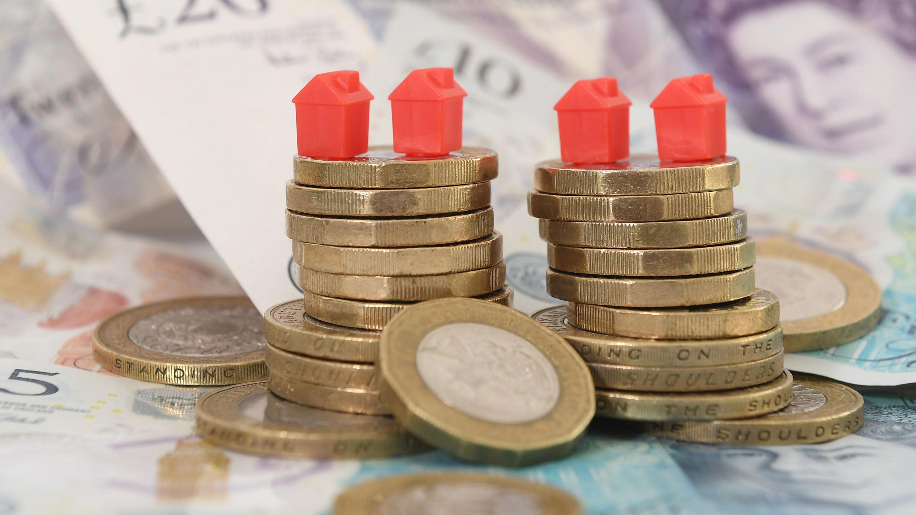 Model houses on a pile of coins and bank notes