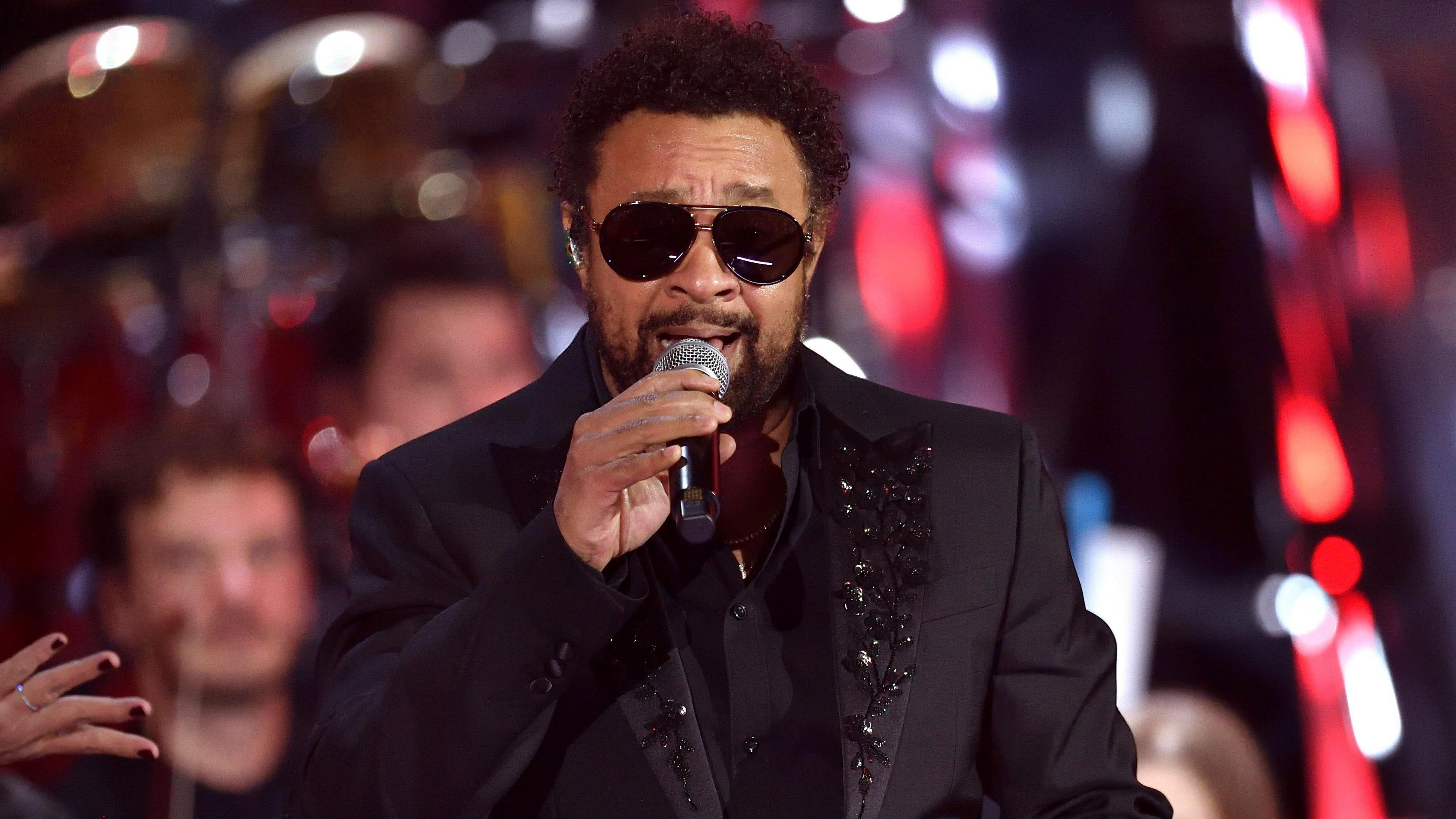Shaggy performing in 2021, wearing a black, bejewelled suit jacket and sunglasses.