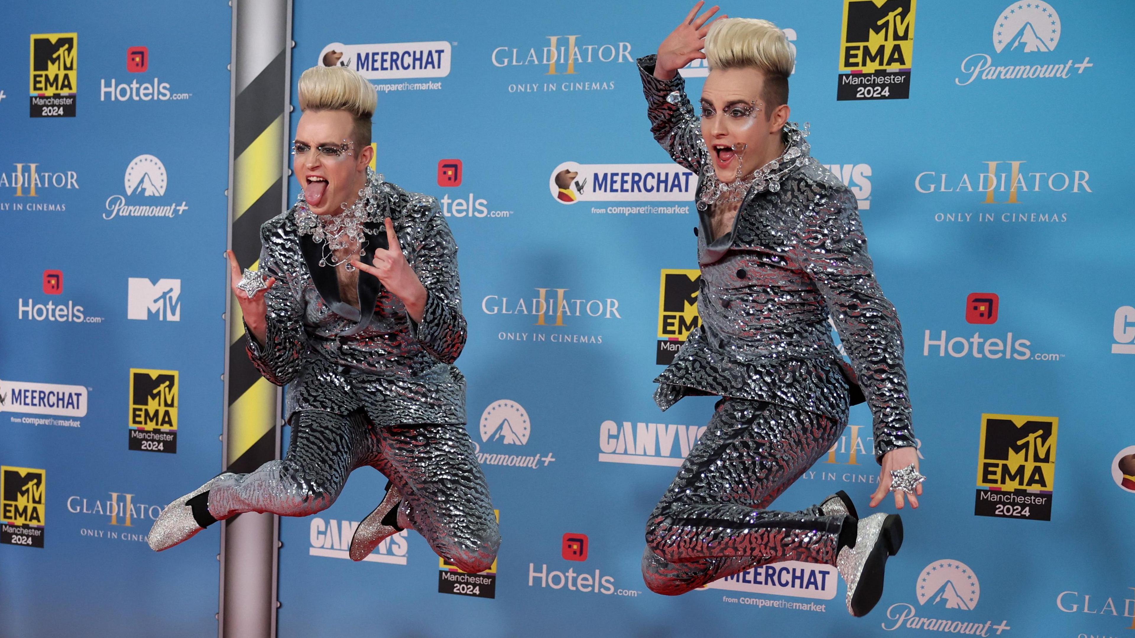 Jedward in mid air and pulling poses in sparking silver suits