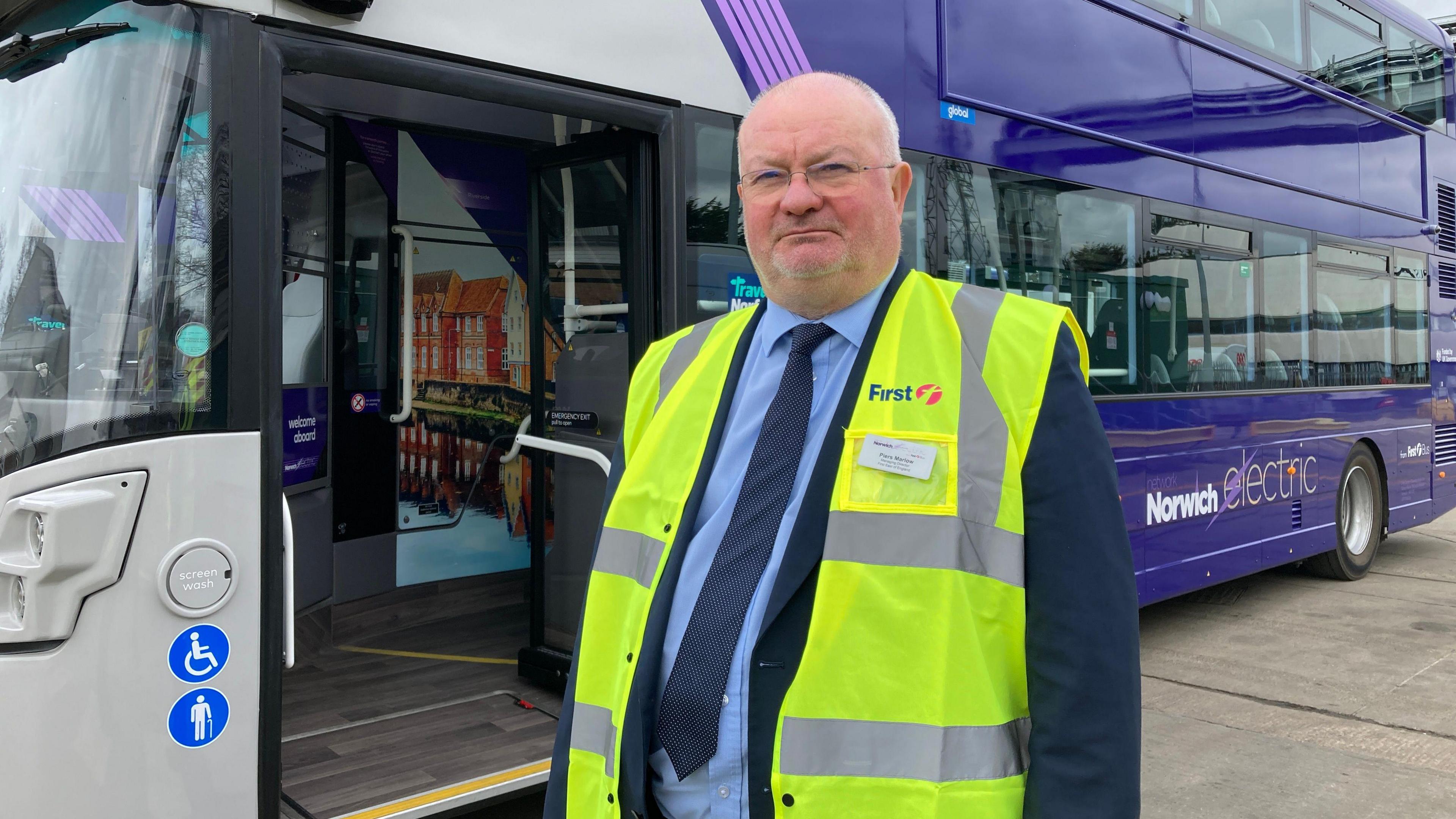 Piers Marlow wearing a blue shirt, navy tie and suit with an illuminous safety vest over the top.