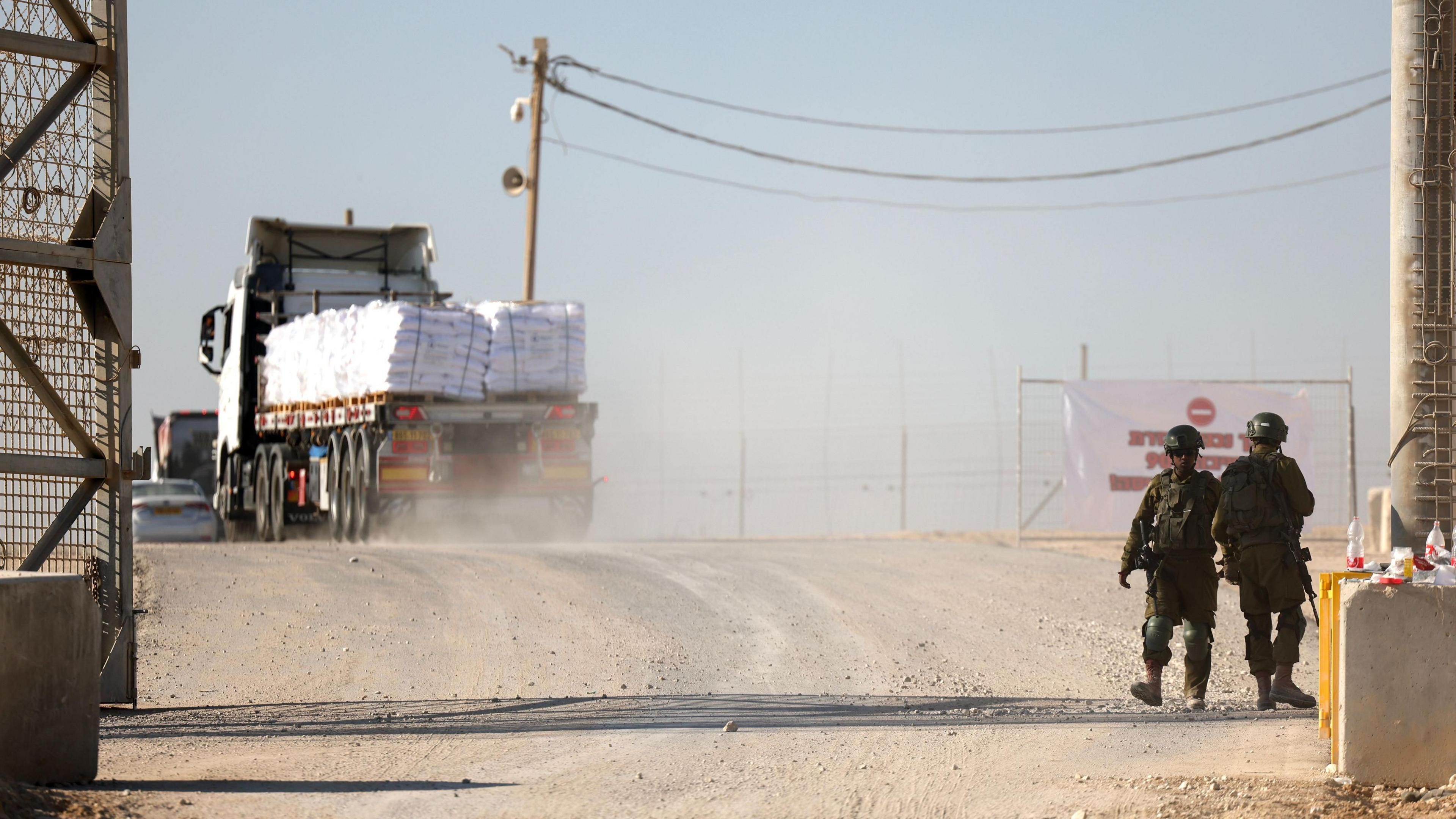 Israeli soldiers stand guard at a gate after a World Food Programme (WFP) aid convoy passes through the Erez West border crossing with the northern Gaza Strip, in southern Israel (11 November 2024)