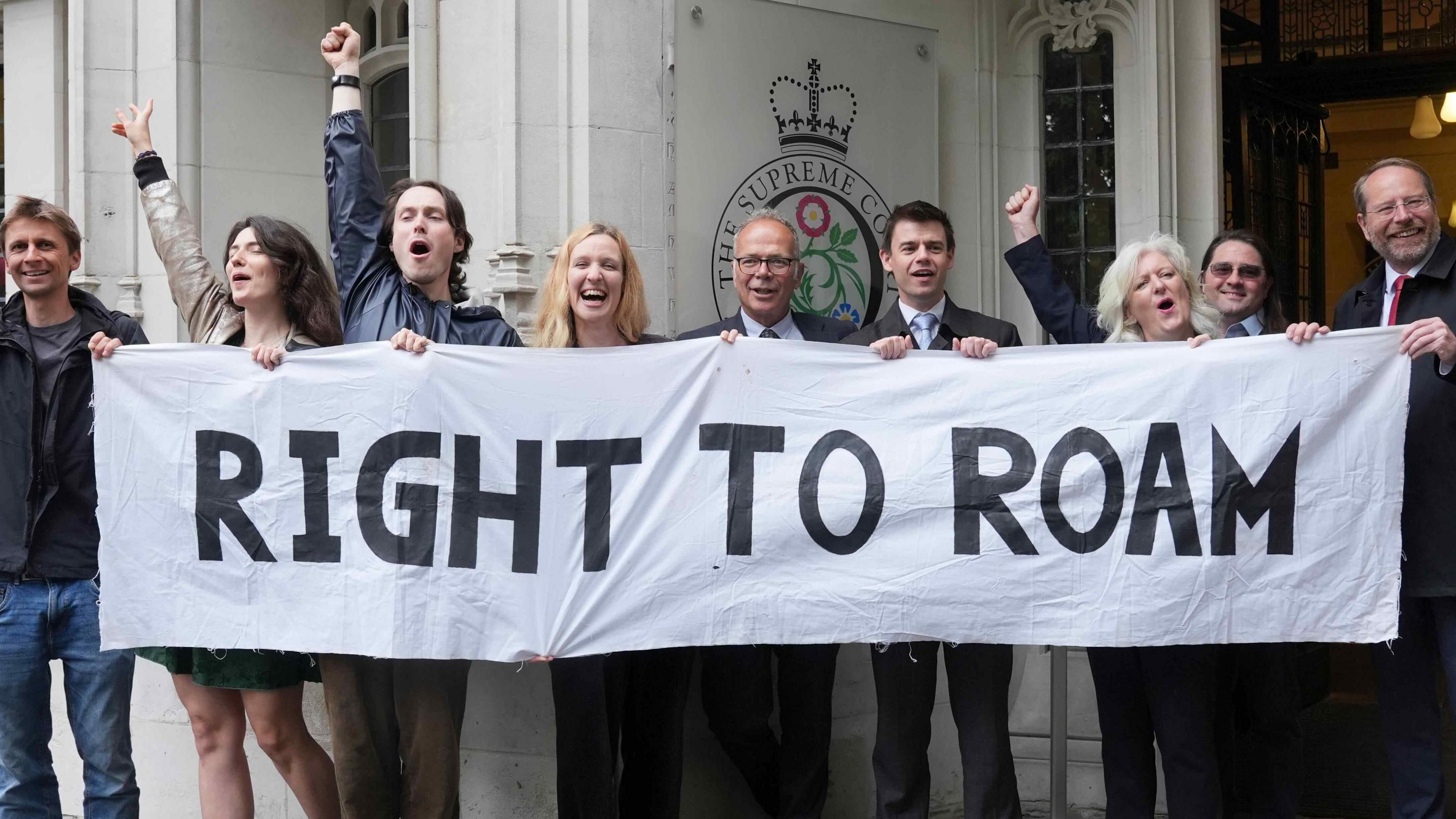 A number of people celebrating behind a banner that says "right to roam"