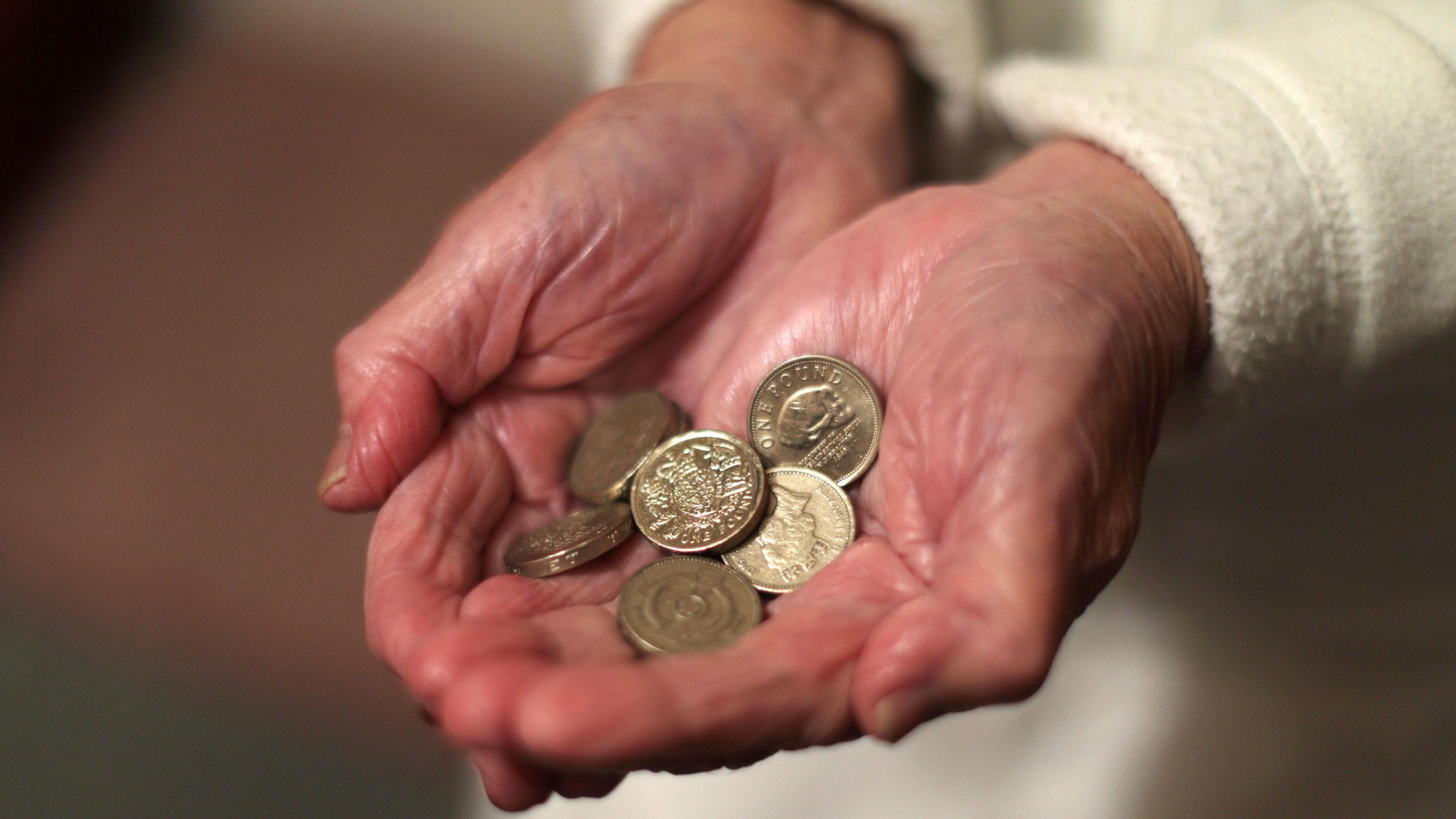 An elderly woman holding pound coins in her hands