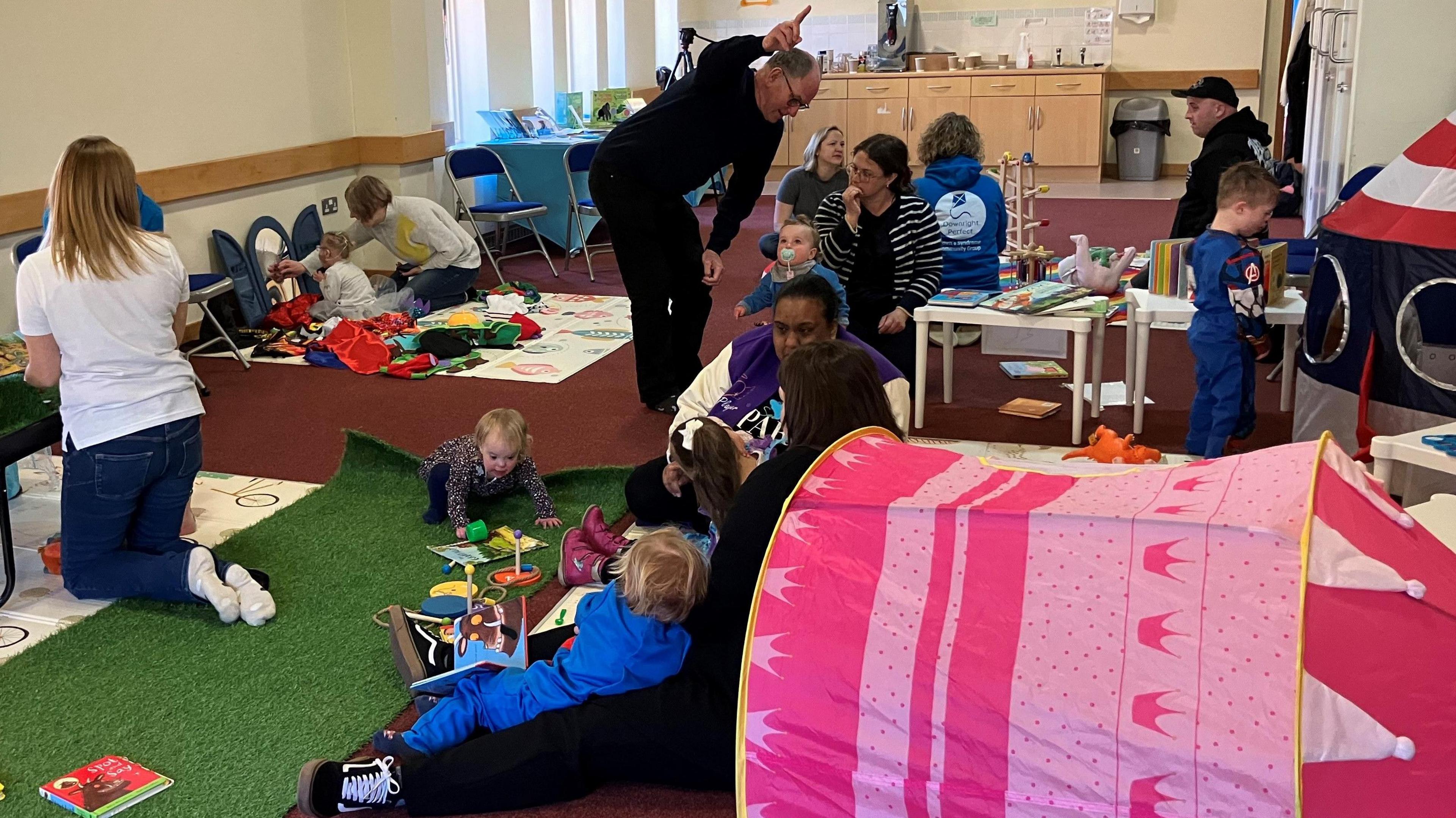 A group of young children playing at a nursery class, with families and staff