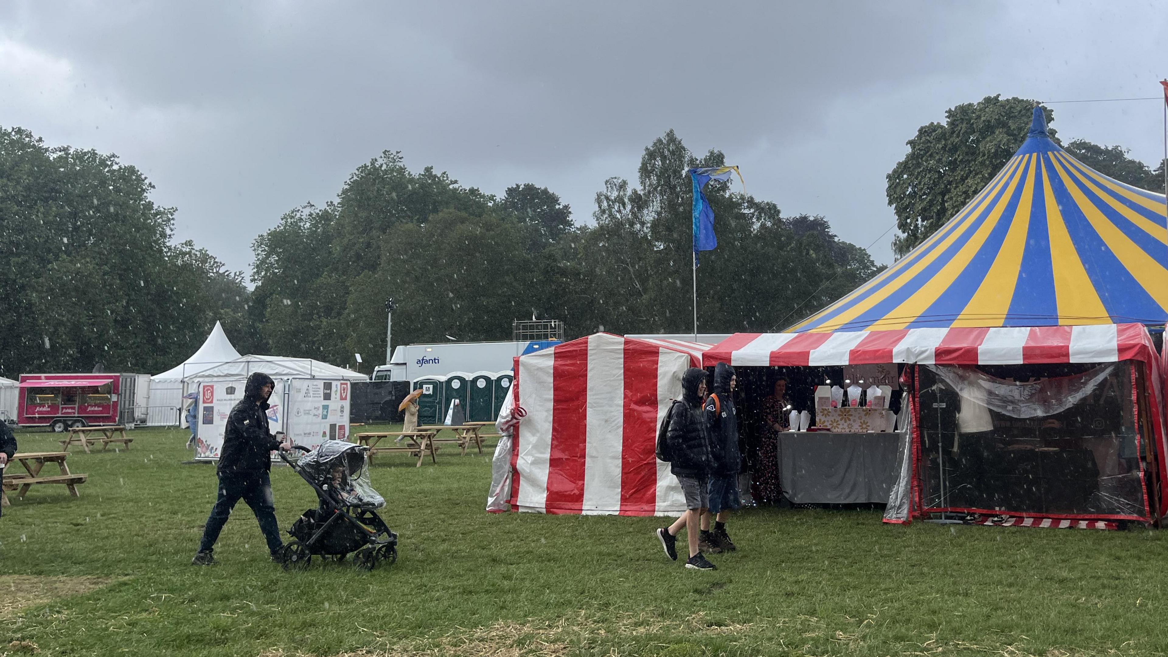 People in raincoats during a downpour at Tafwyl festival