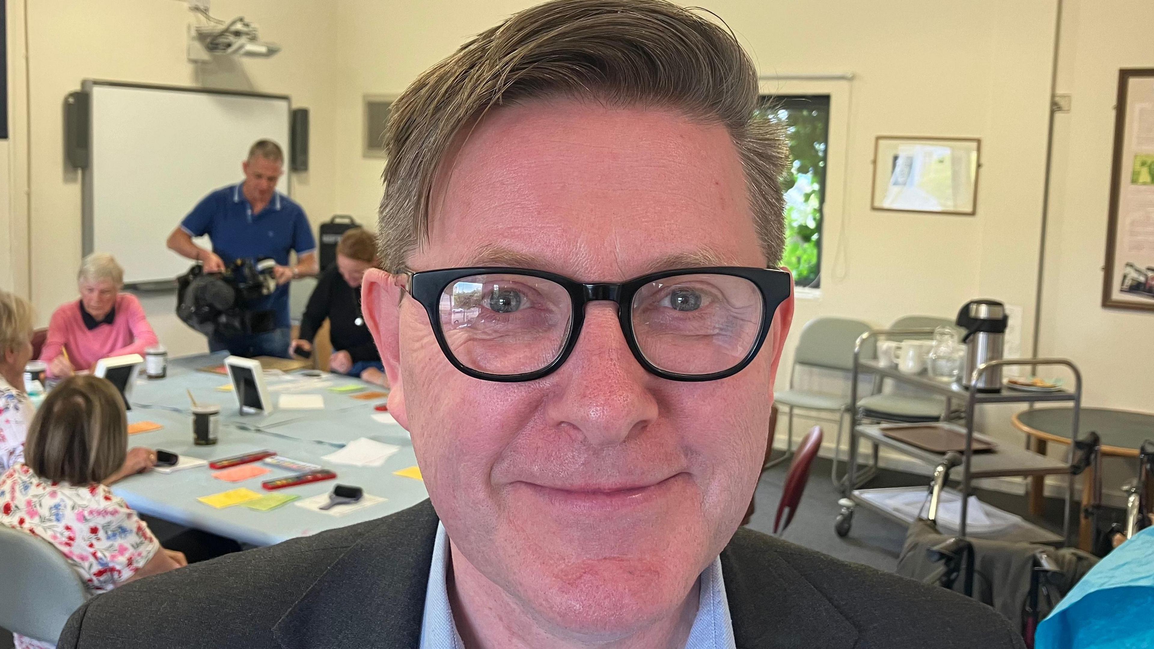 A man in an art class smiling at the camera