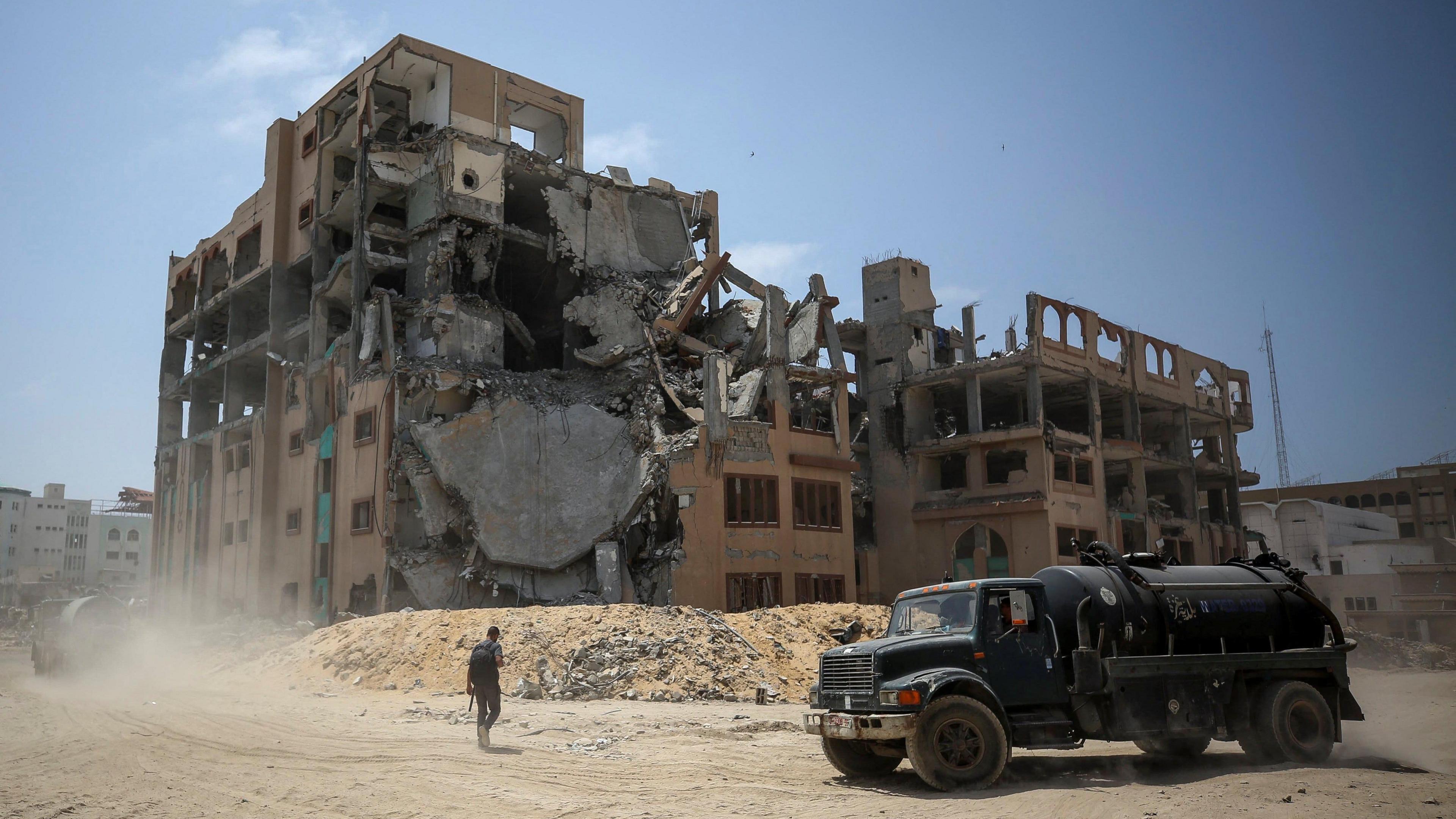 A truck in front of a building in ruins.