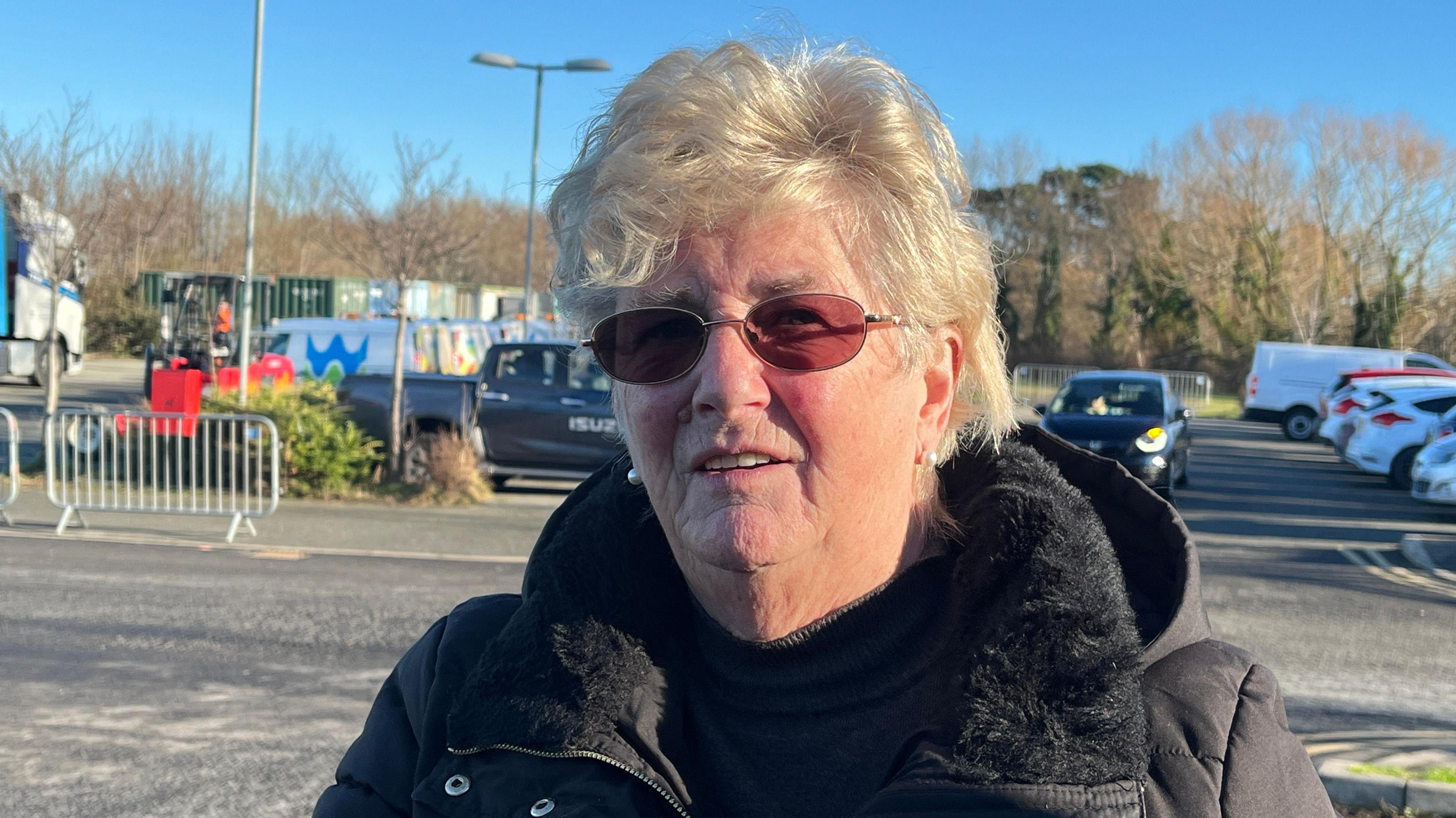 Ann Parry pictured at Eirias Park in the sunshine. She wears sunglasses and looks into the camera. 