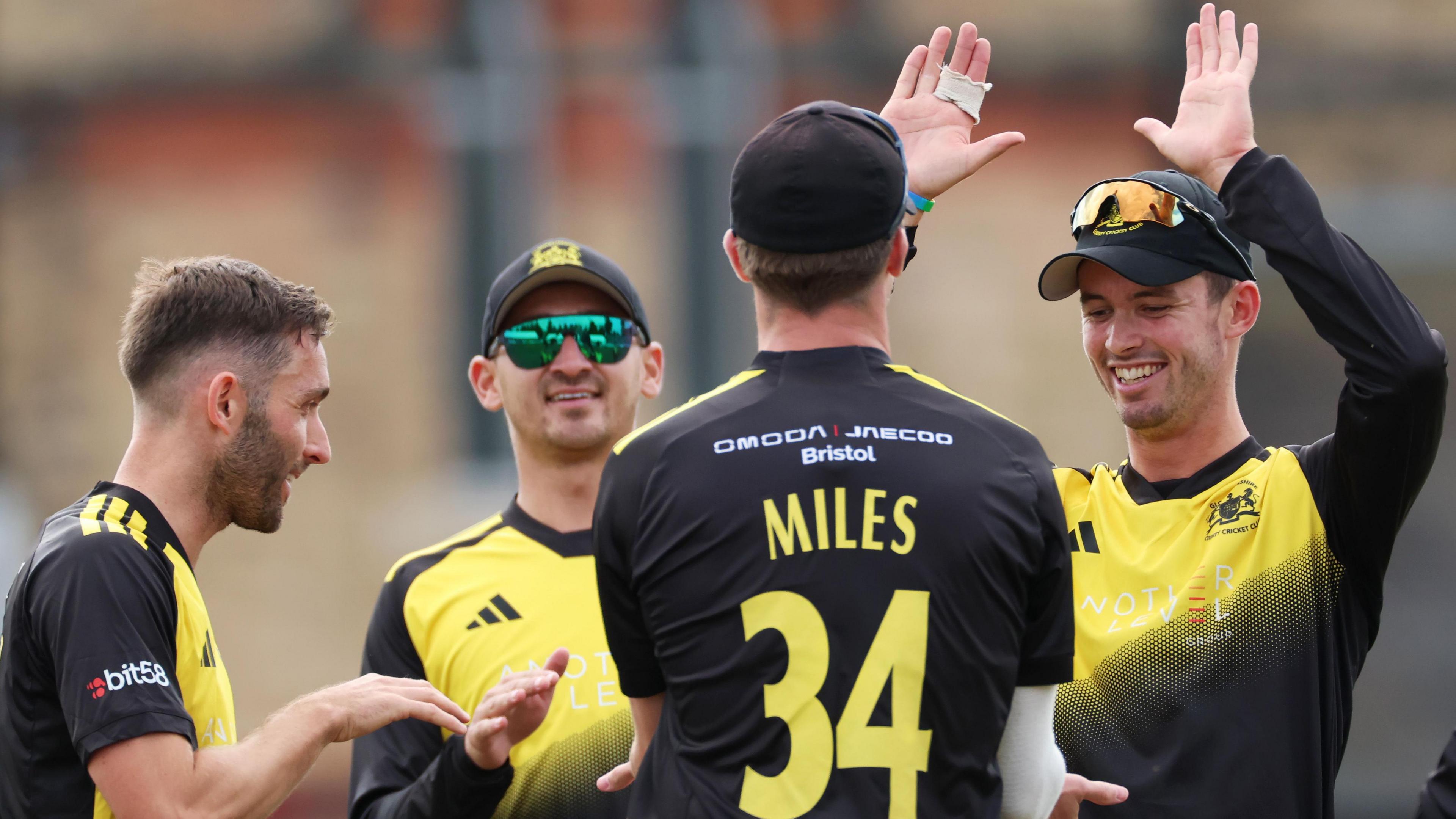 Gloucestershire players celebrate a wicket with Craig Miles (with his back turned) getting a high-five