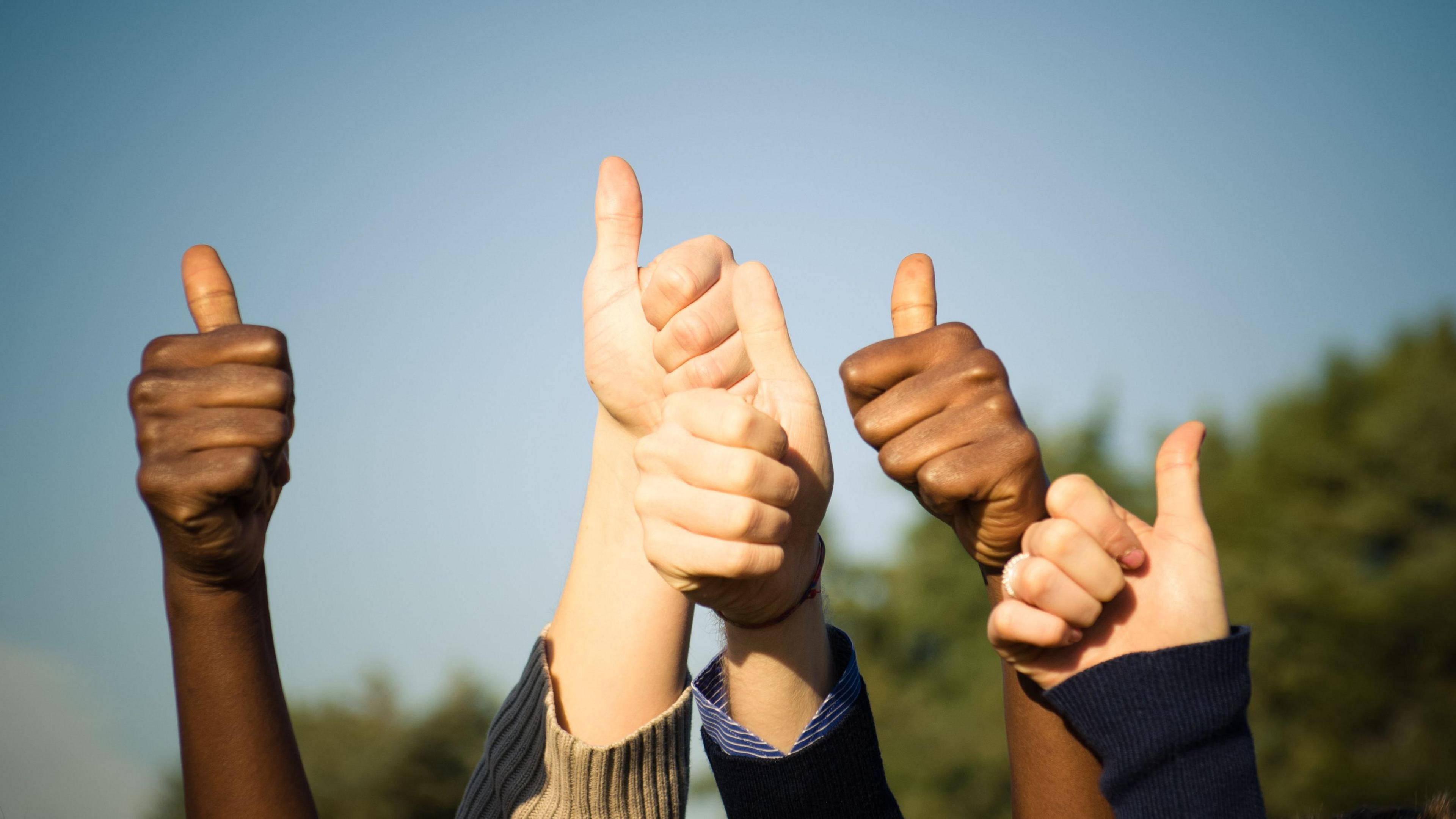 Children put their hands in the air, making thumbs up signs
