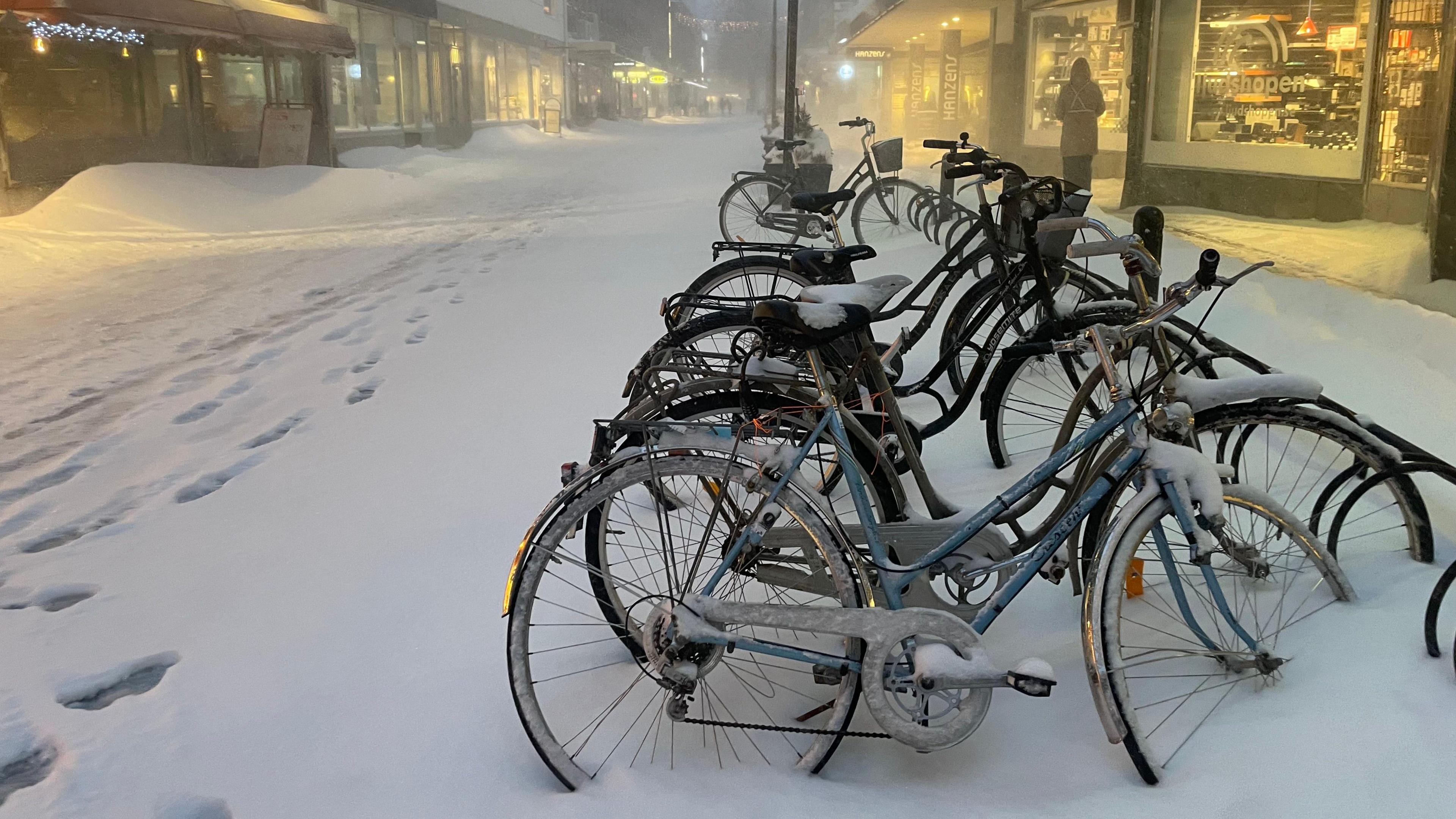 Bicycles covered in snow stand in an almost deserted shopping street in Skellefteå.