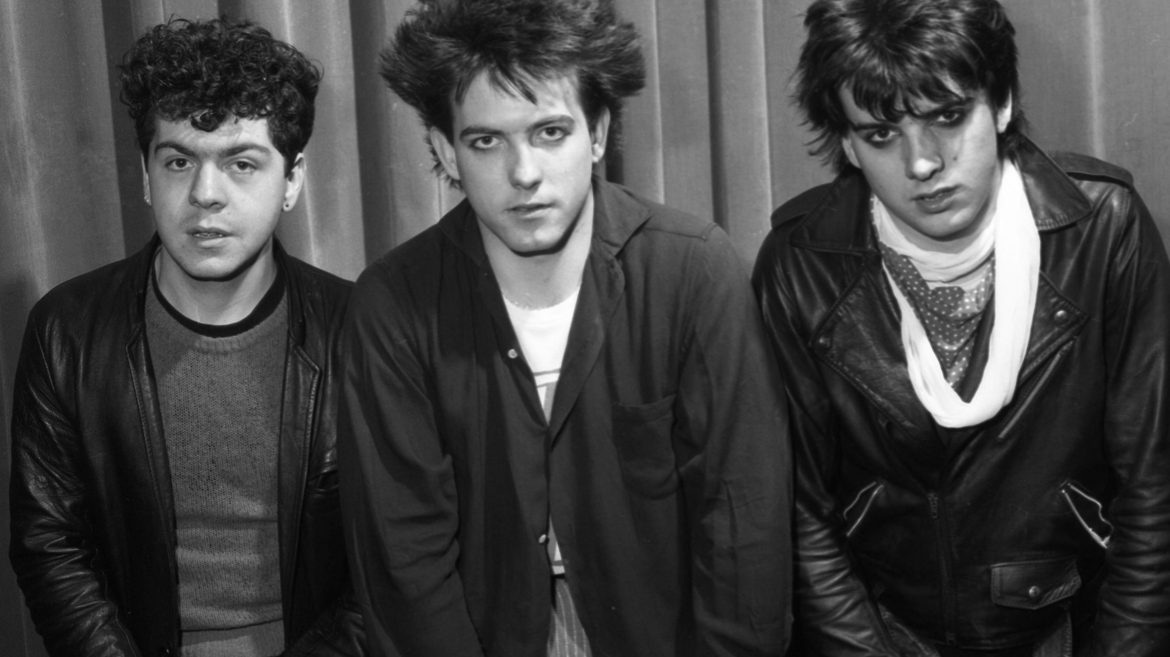 Rock band The Cure, pictured backstage at BBC Top of the Pops in 1981. The image featuring three band members is in black and white, with singer Robert Smith pictured in the centre.  