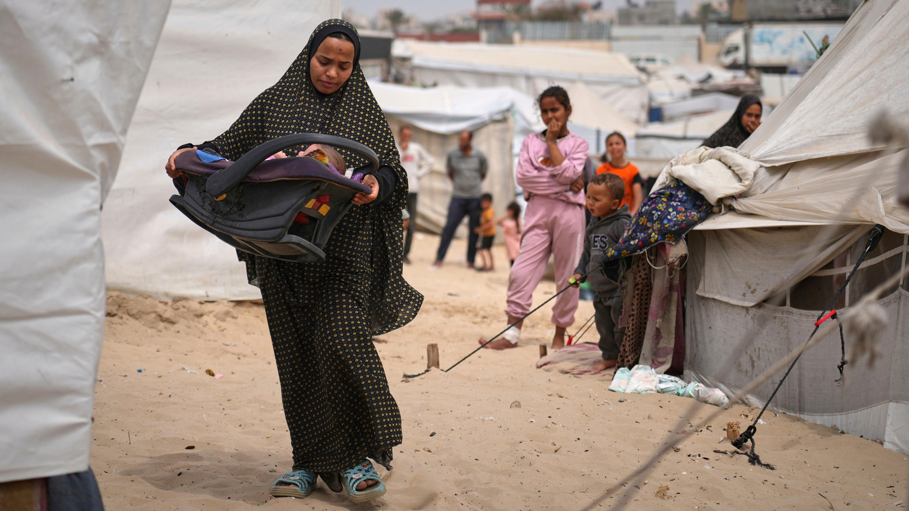 Shaima al-Louh, 24, carries her three-month-old daughter, Jilan Zarrouk, at a makeshift tent camp for displaced Palestinians in al-Mawasi, on the outskirts of Khan Younis in the southern Gaza Strip (9 April 2025)