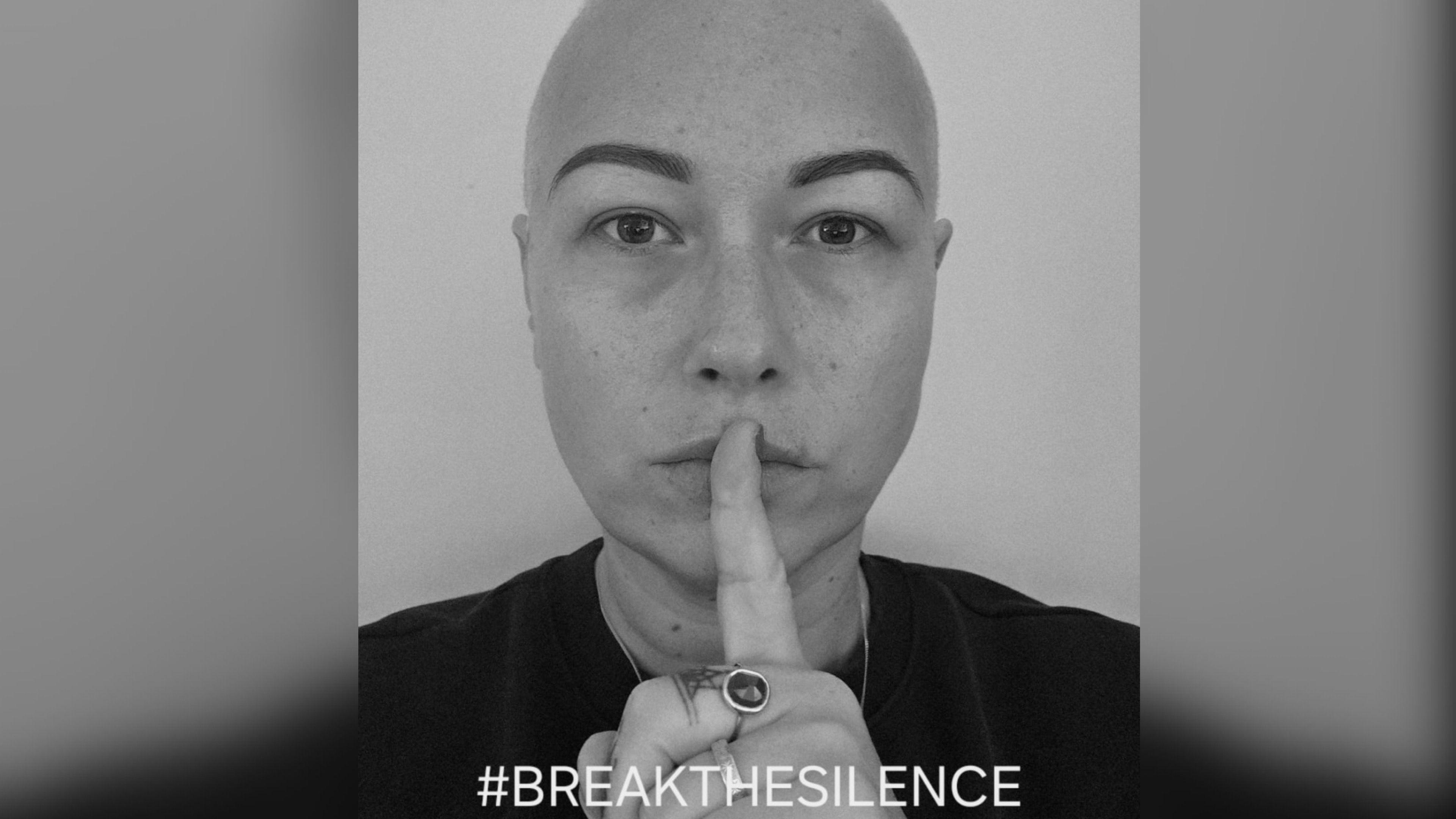 Black and white close up of a woman with a finger on her lips and the hashtag breakthesilence