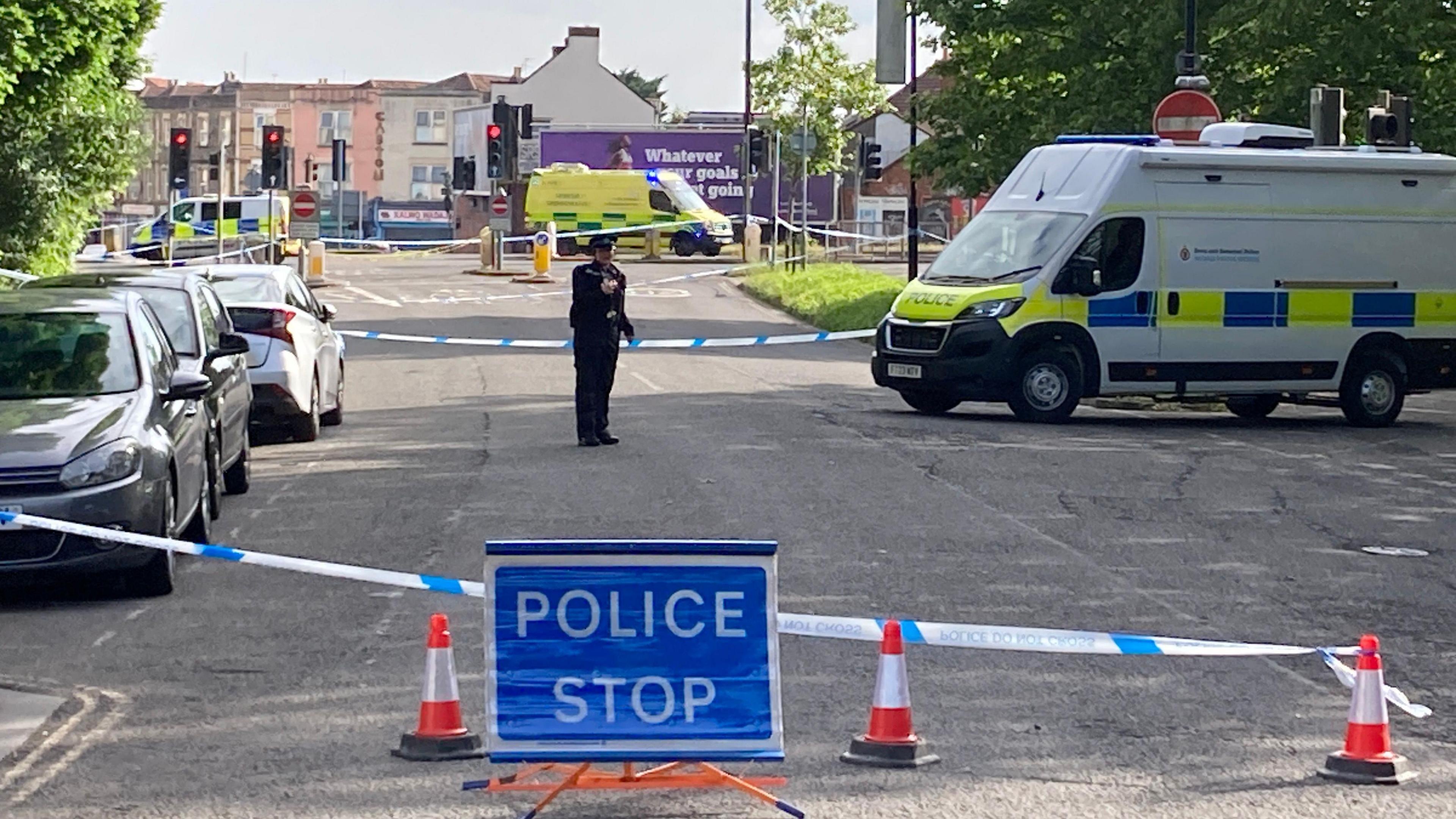 Cordon blocking off a road, with police stop sign and van