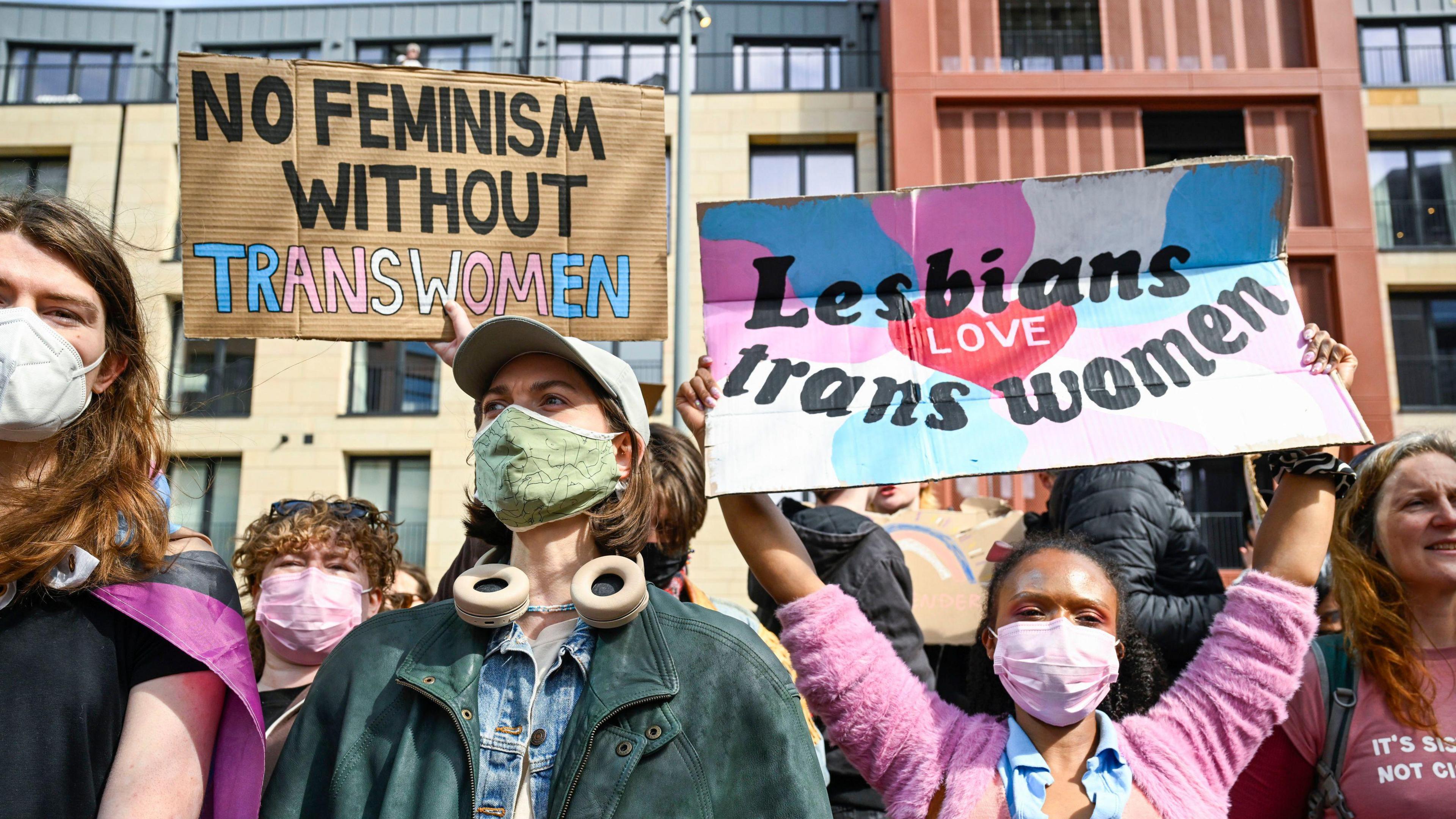 Protestors holding signs up at a rally to show support for the trans community and express anger at the Supreme Court - the placards read "no feminism without trans women" and "lesbians love trans women".