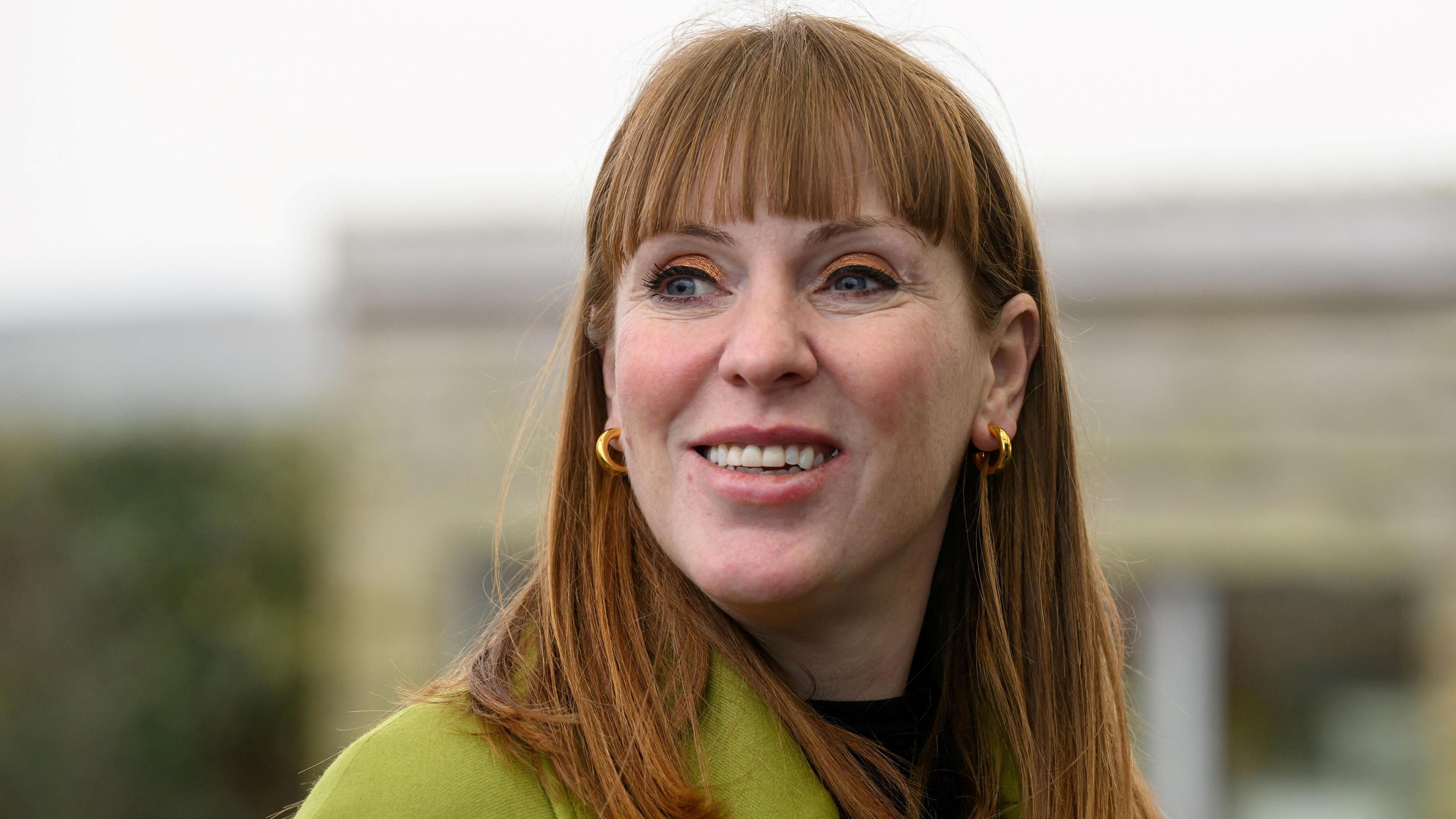 British Deputy Prime Minister Angela Rayner on a visit to Newquay Orchard in February, photo is a headshot where she is wearing a lime green coat