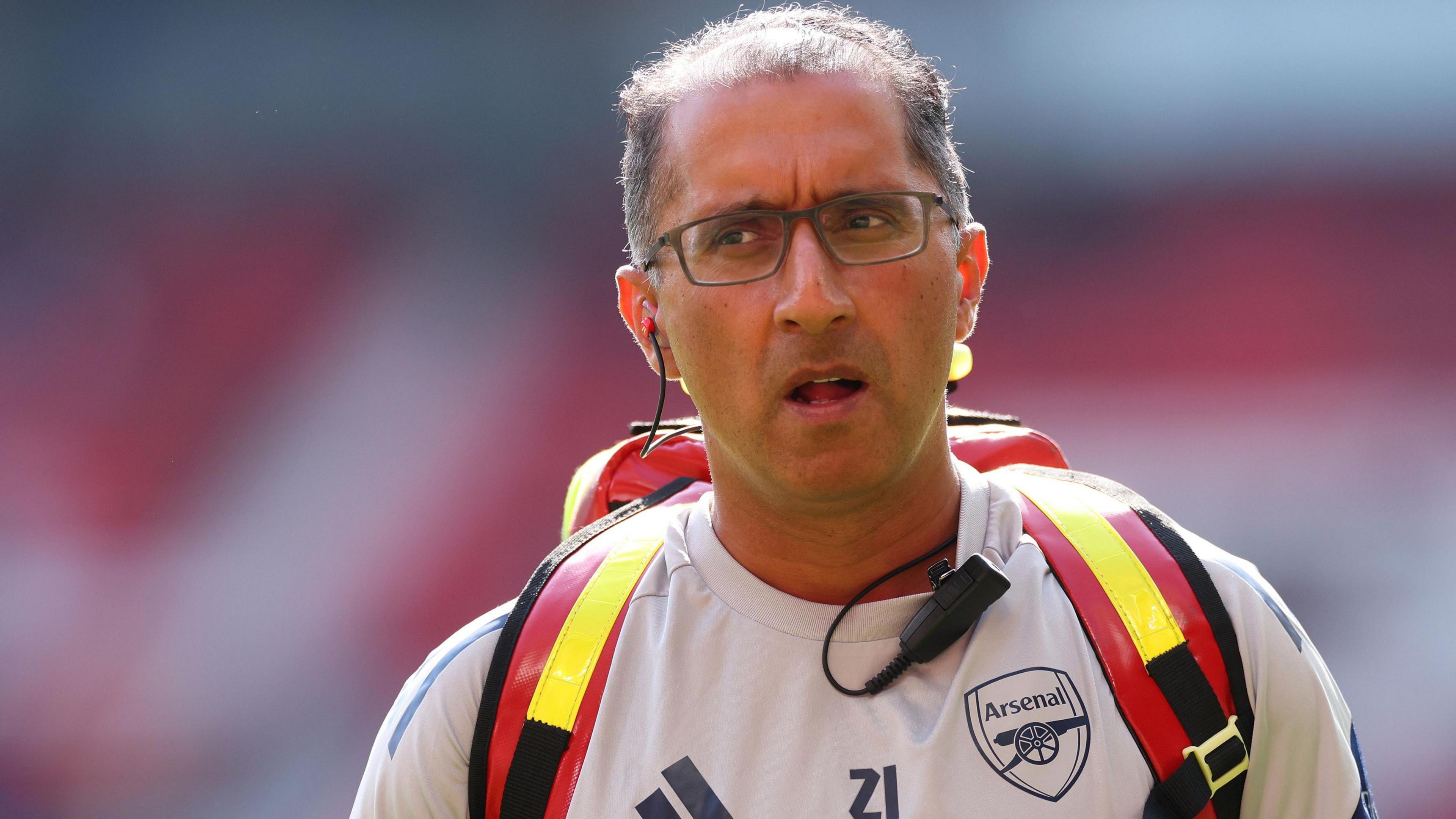 Dr Zafar Iqbal wearing an Arsenal training top and medical rucksack
