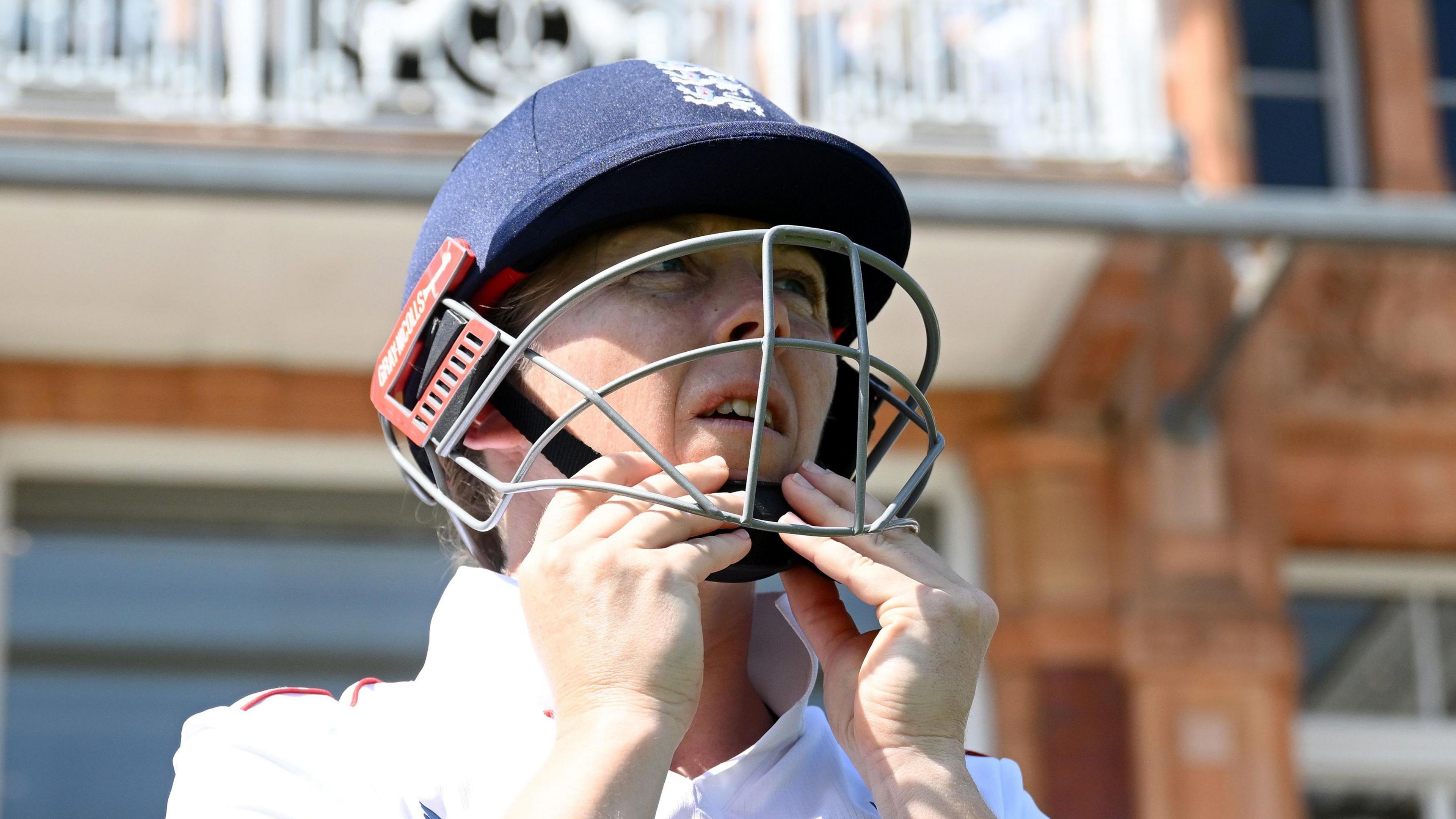 Heather Knight putting on her batting helmet in front of the Lord's pavilion