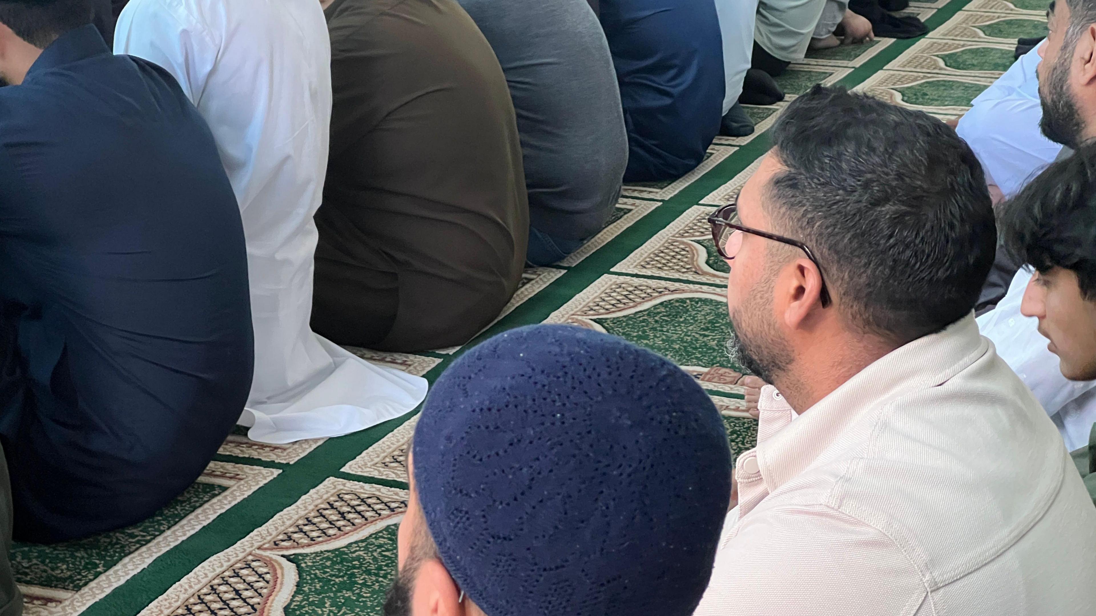 Men sitting down for prayers in a row 