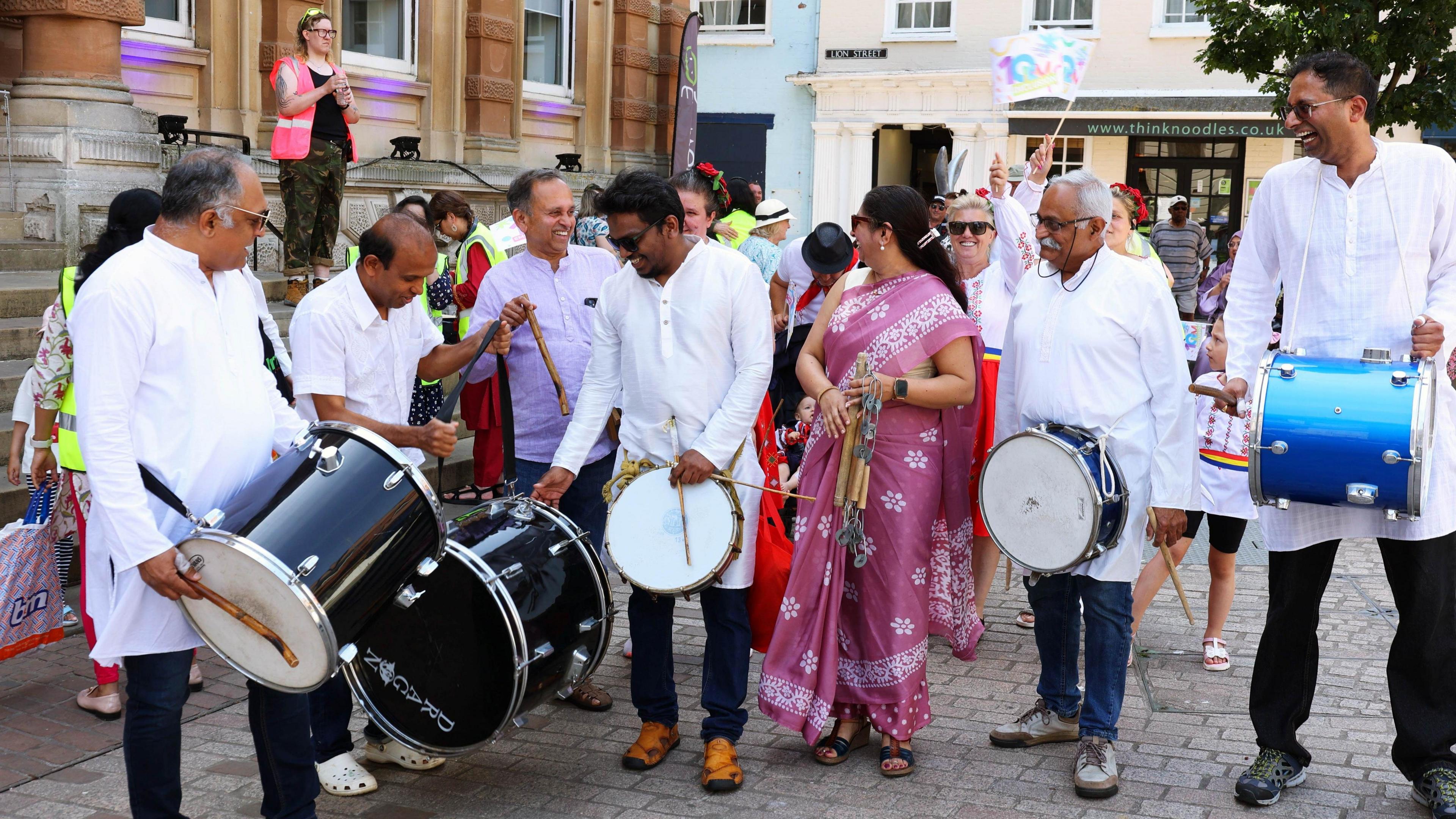 Six people with drums stand outside Ipswich Town hall.