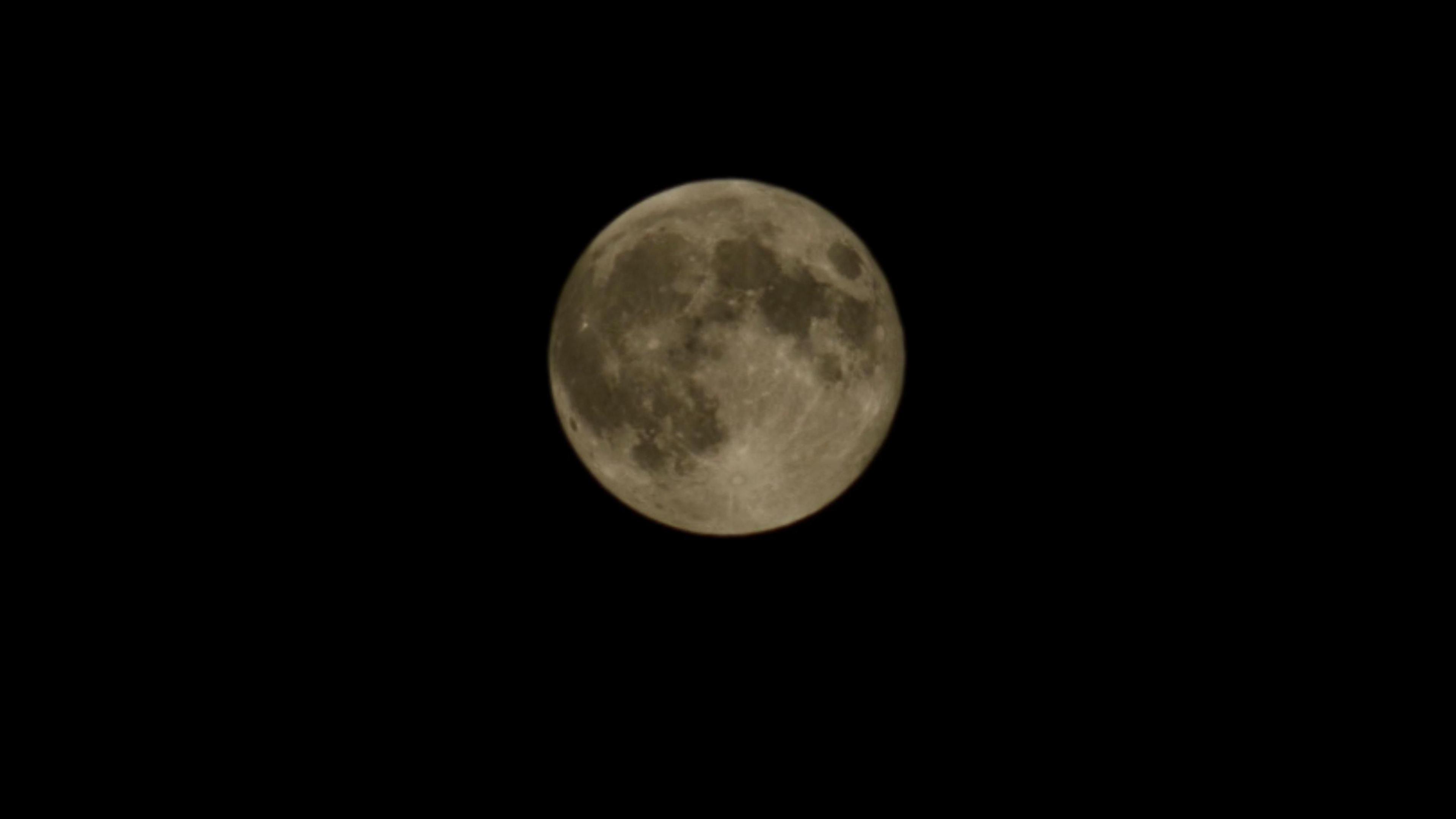 A mid-shot of a grey coloured moon in a dark sky