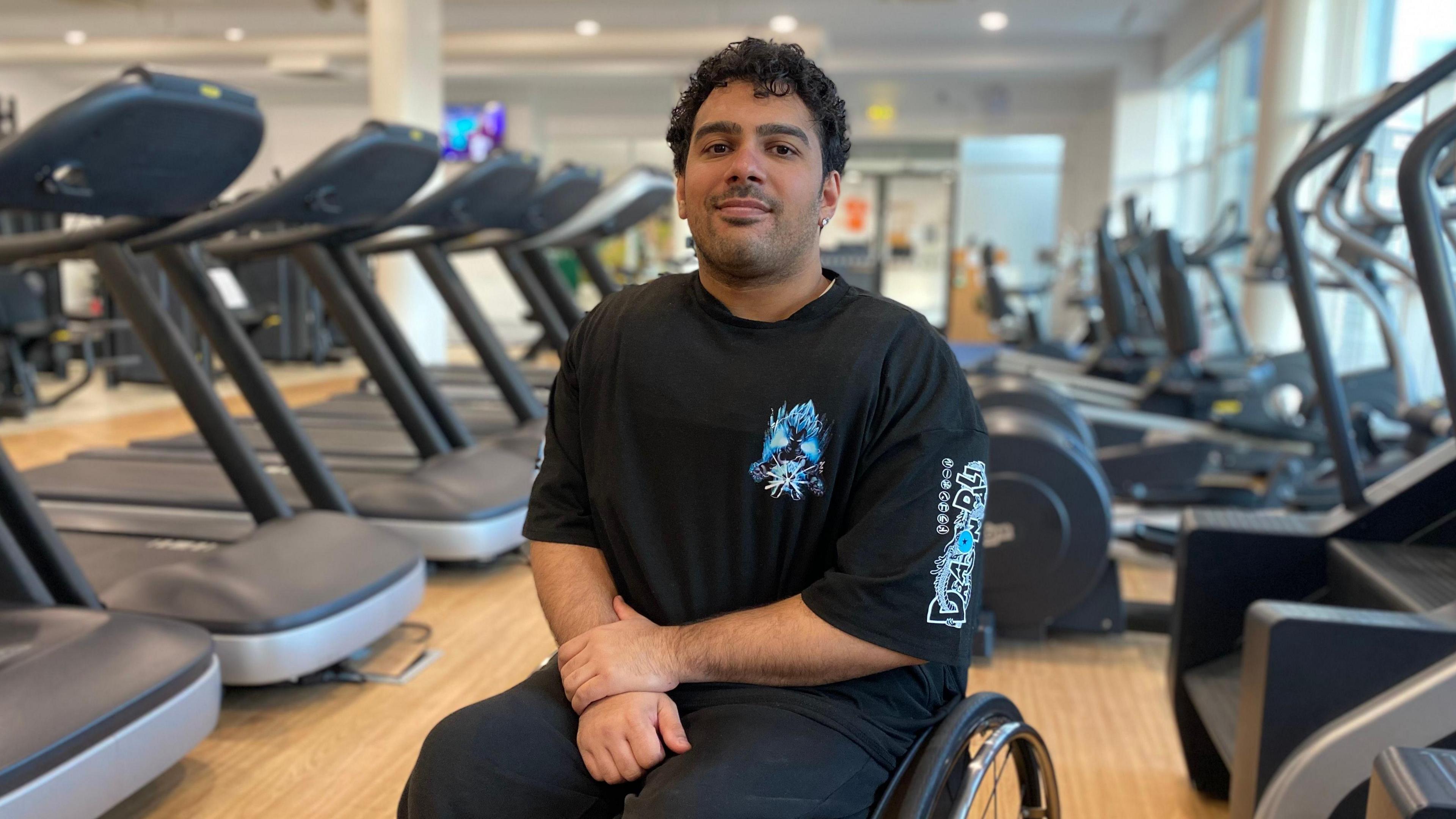 Robert in the gym with treadmills behind him