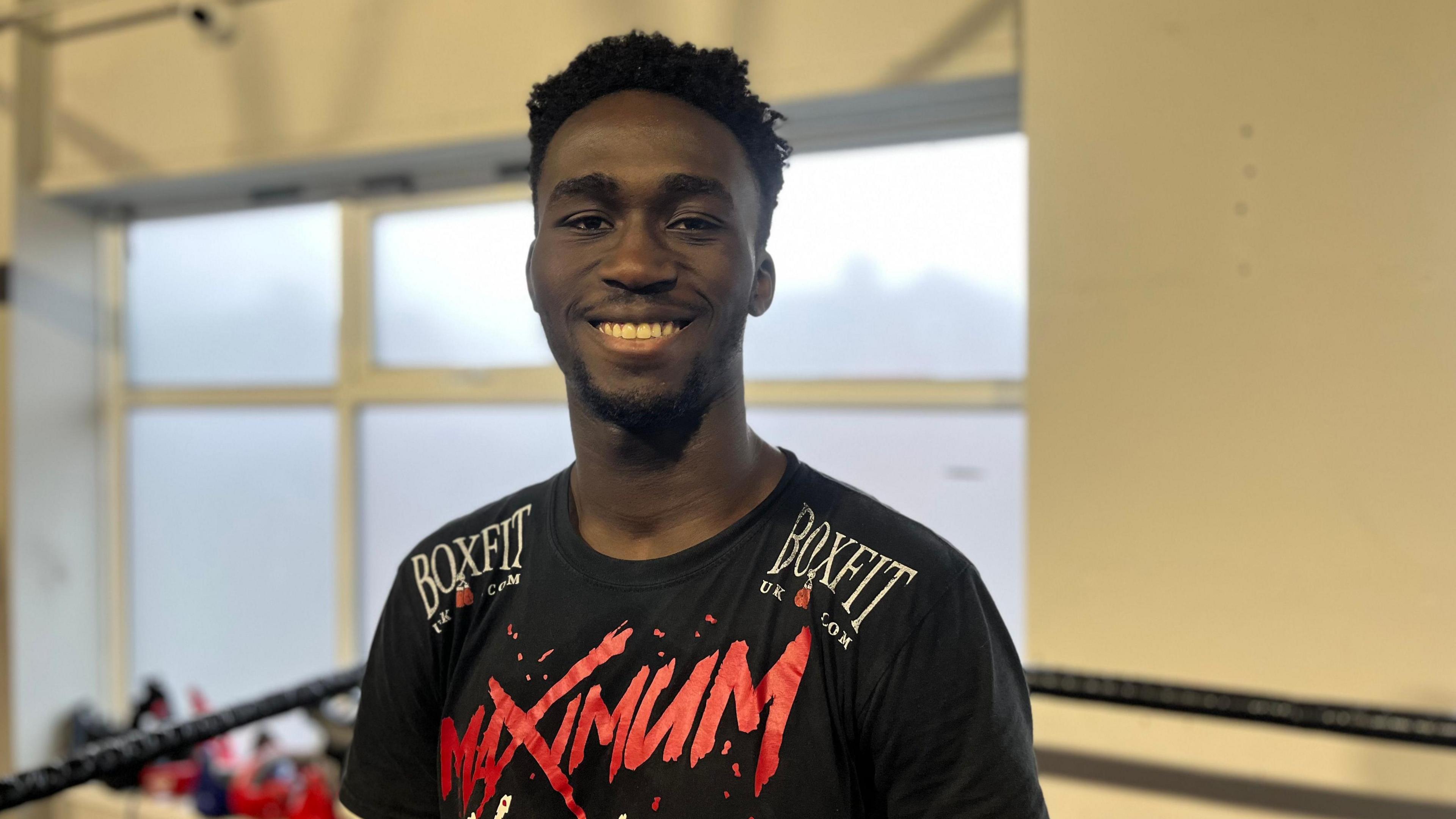 Adam Olaore smiling in a boxing ring