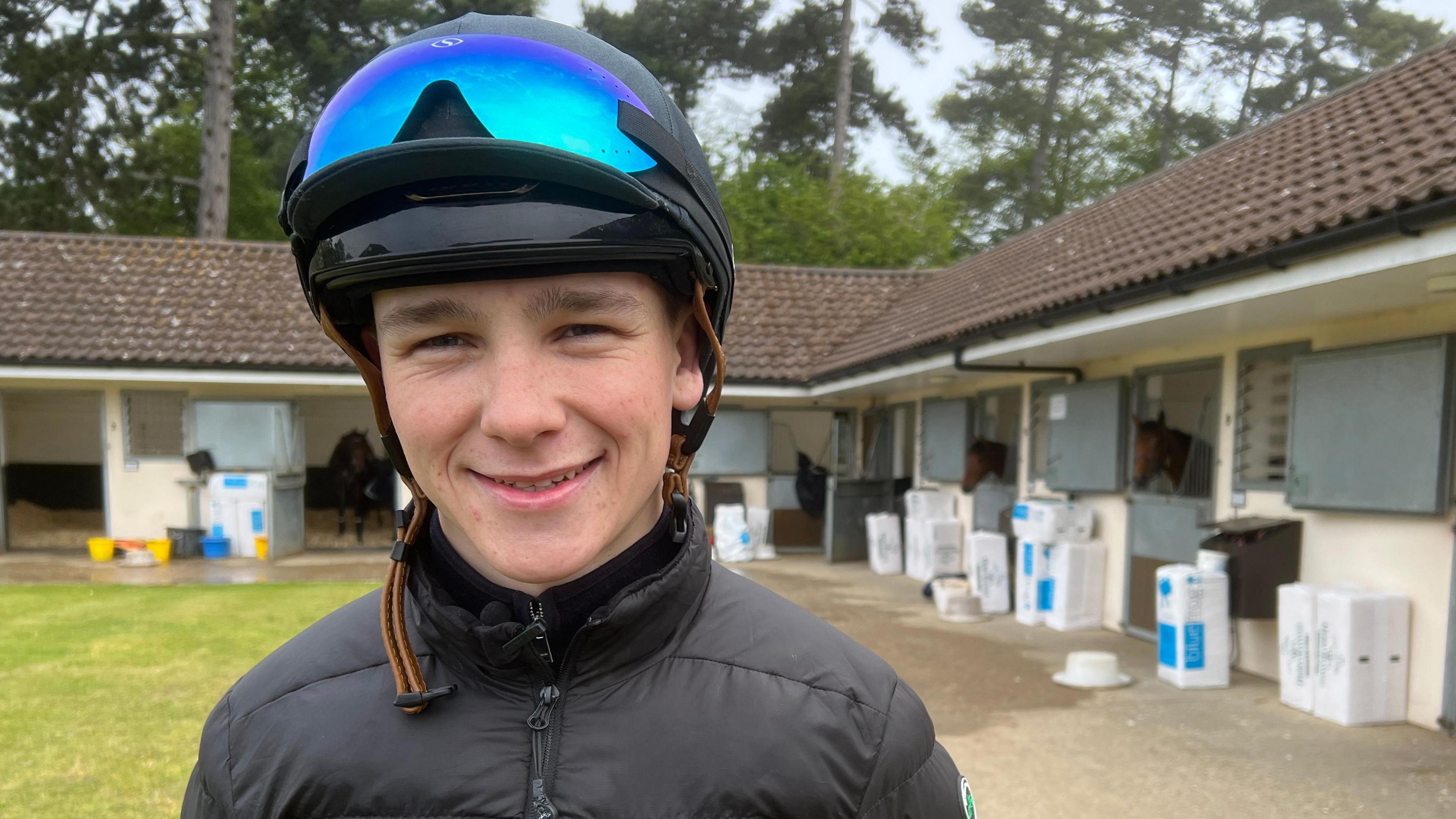 Jockey Billy Loughnane standing in his racing hat with visor at the Craven House Stables in Newmarket.