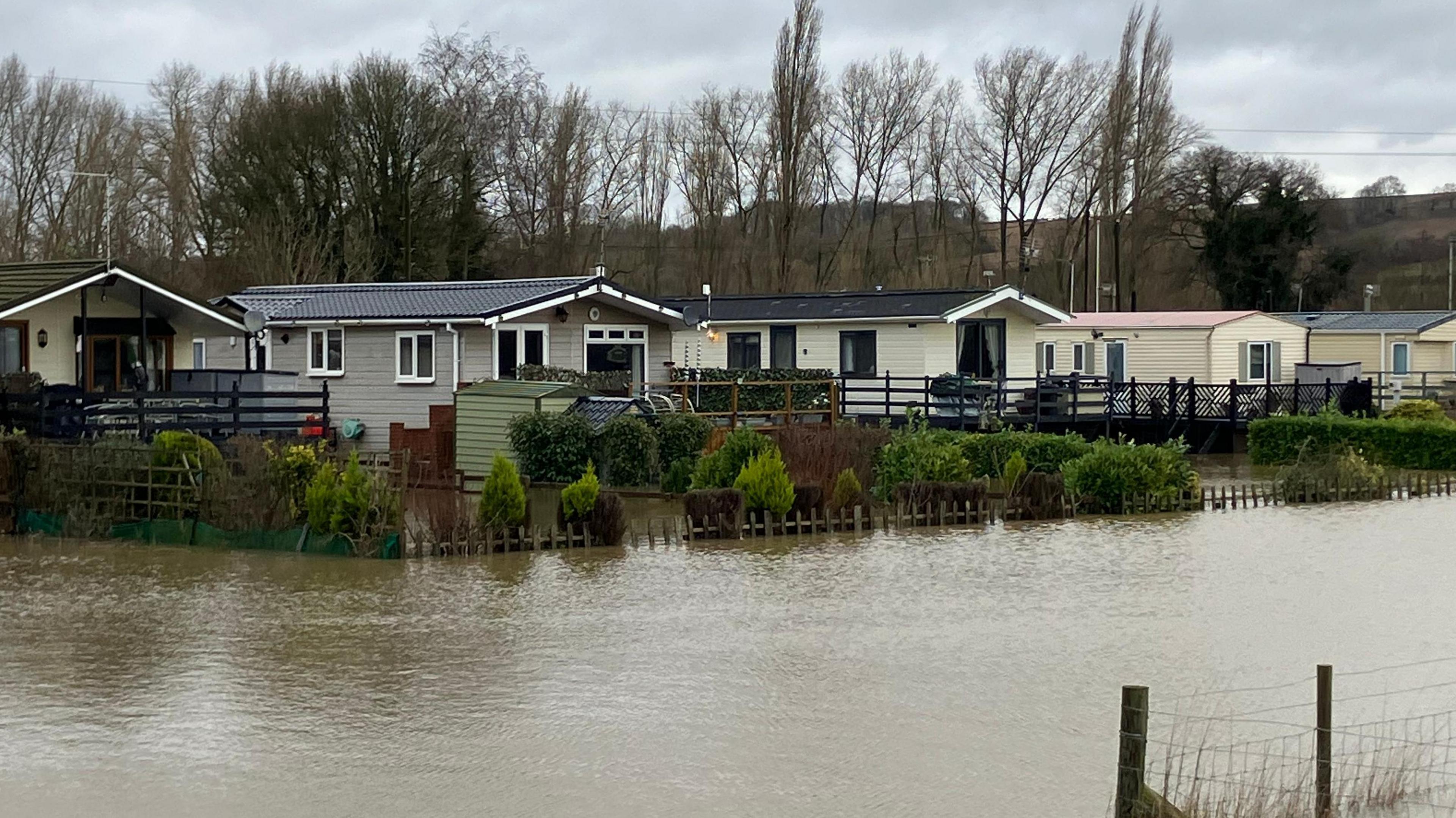 A flooded area beside a number of residential properties in Yalding, Kent. Five properties can be seen elevated from a completely flooded area.