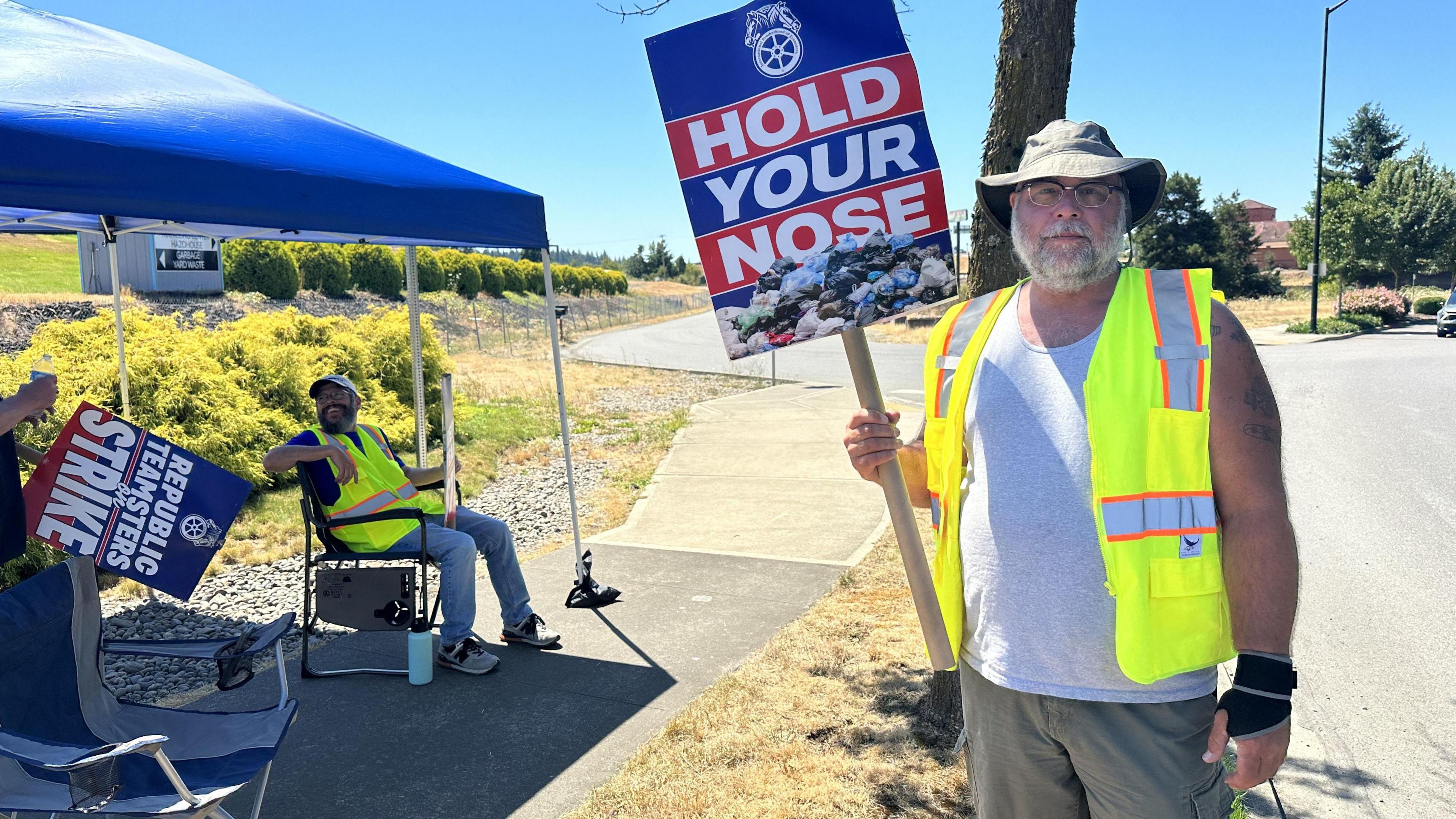 Eric Fiel wears a high-vis yellow vest and holds a sign while picketing with the Teamster