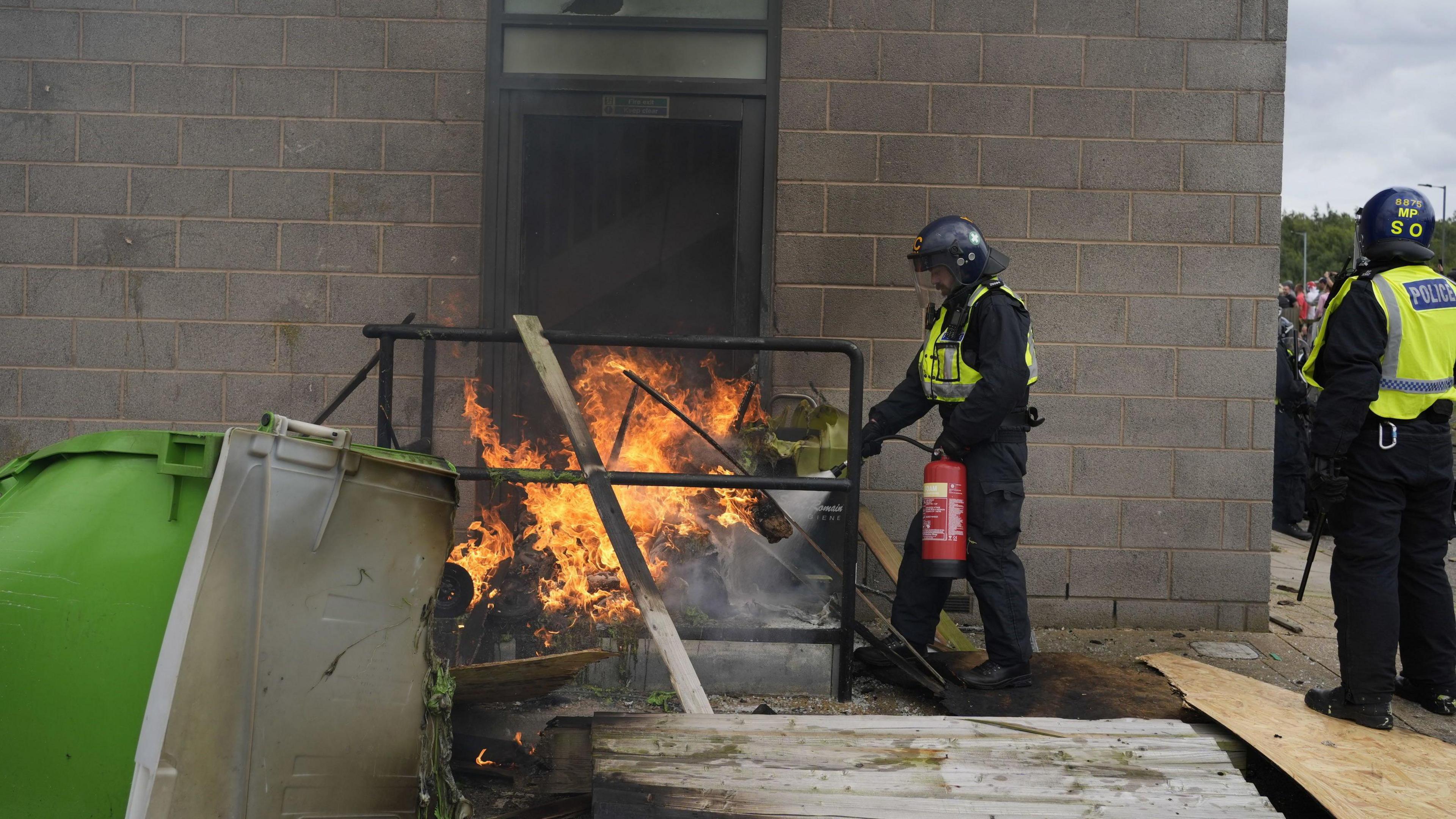 A fire is extinguished by police officers as trouble flares outside the Holiday Inn Express in Rotherham, South Yorkshire