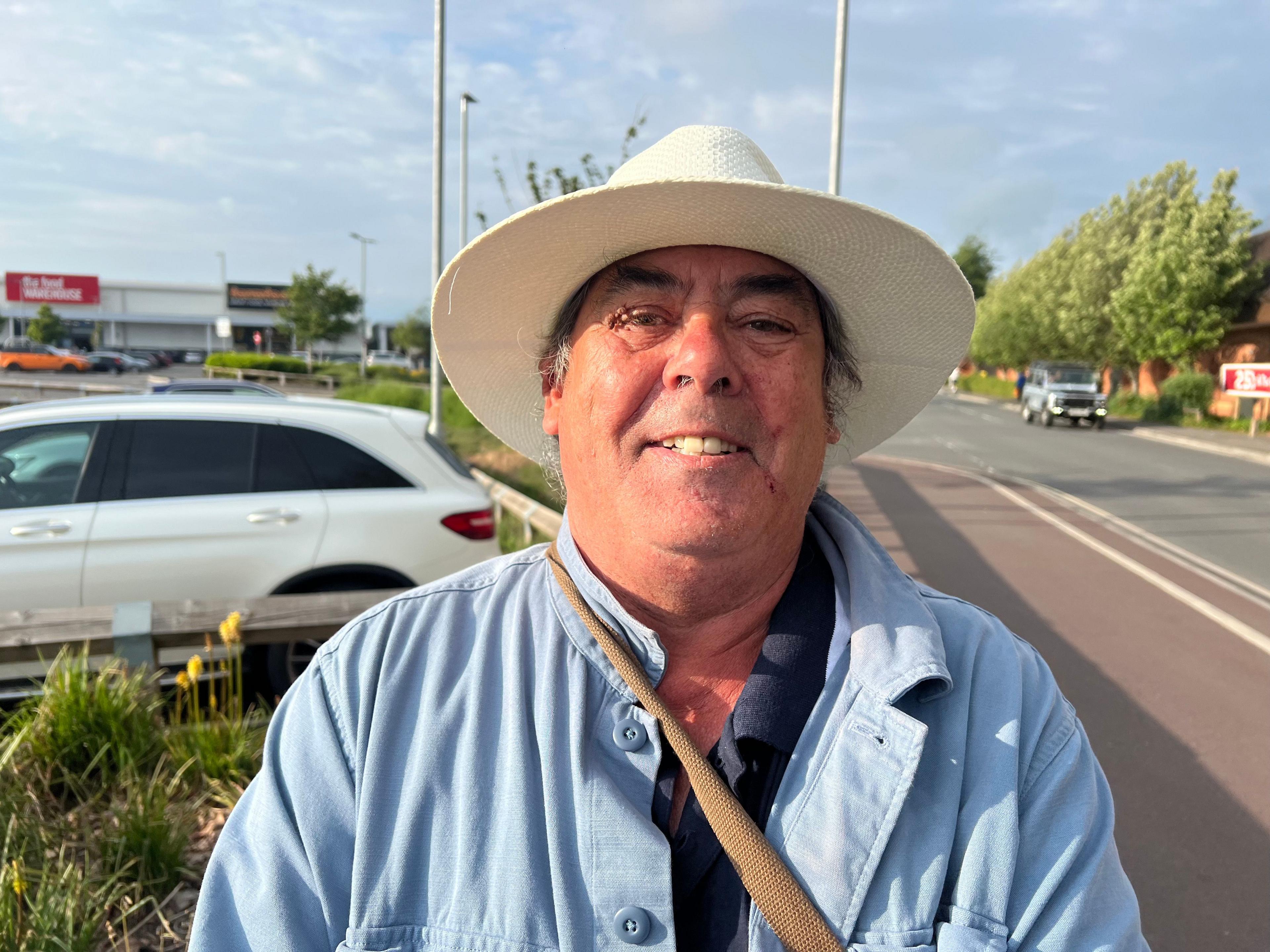 Man in light blue shirt, with off-white sun hat