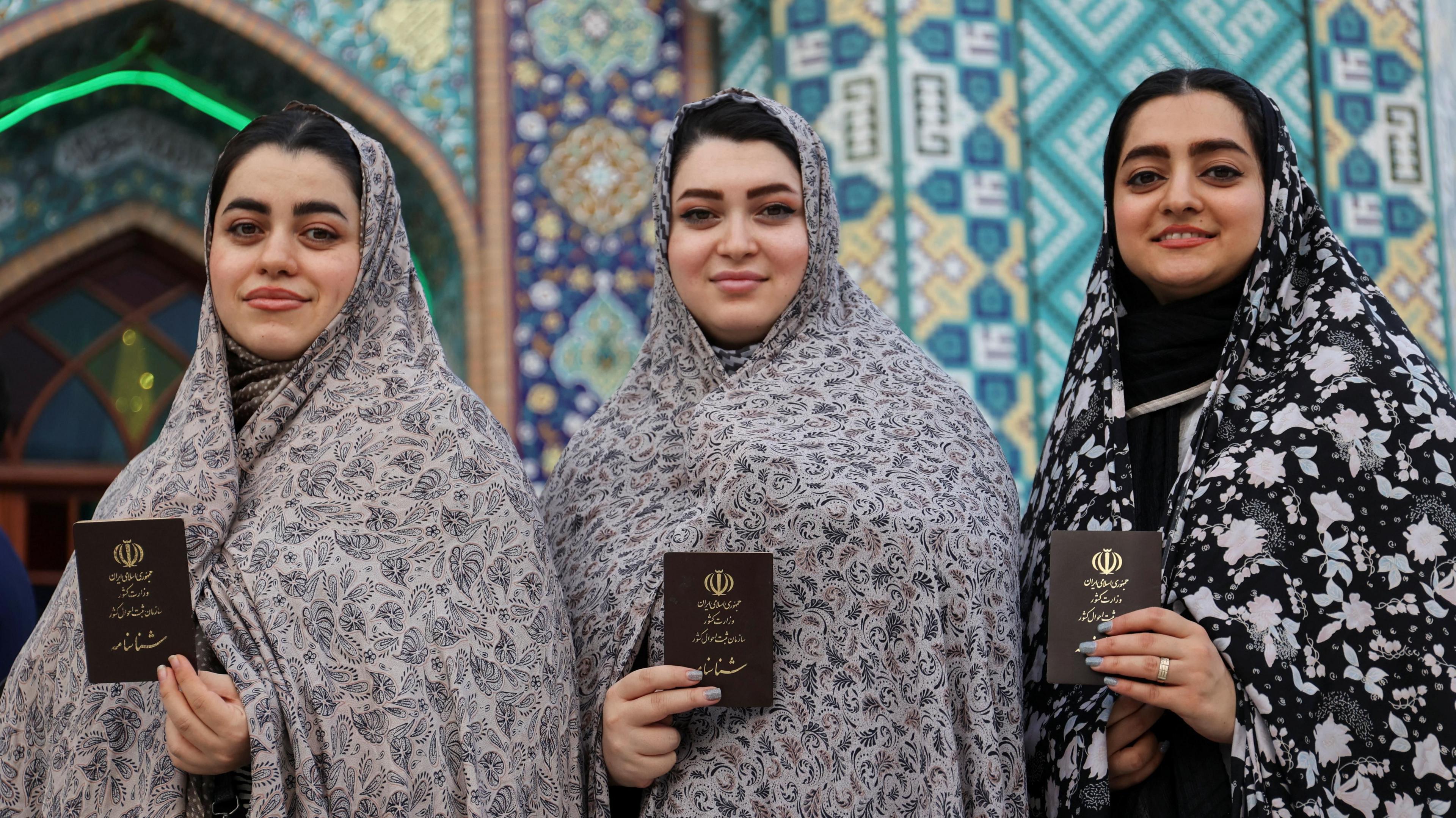 Three women holding their documents and smiling