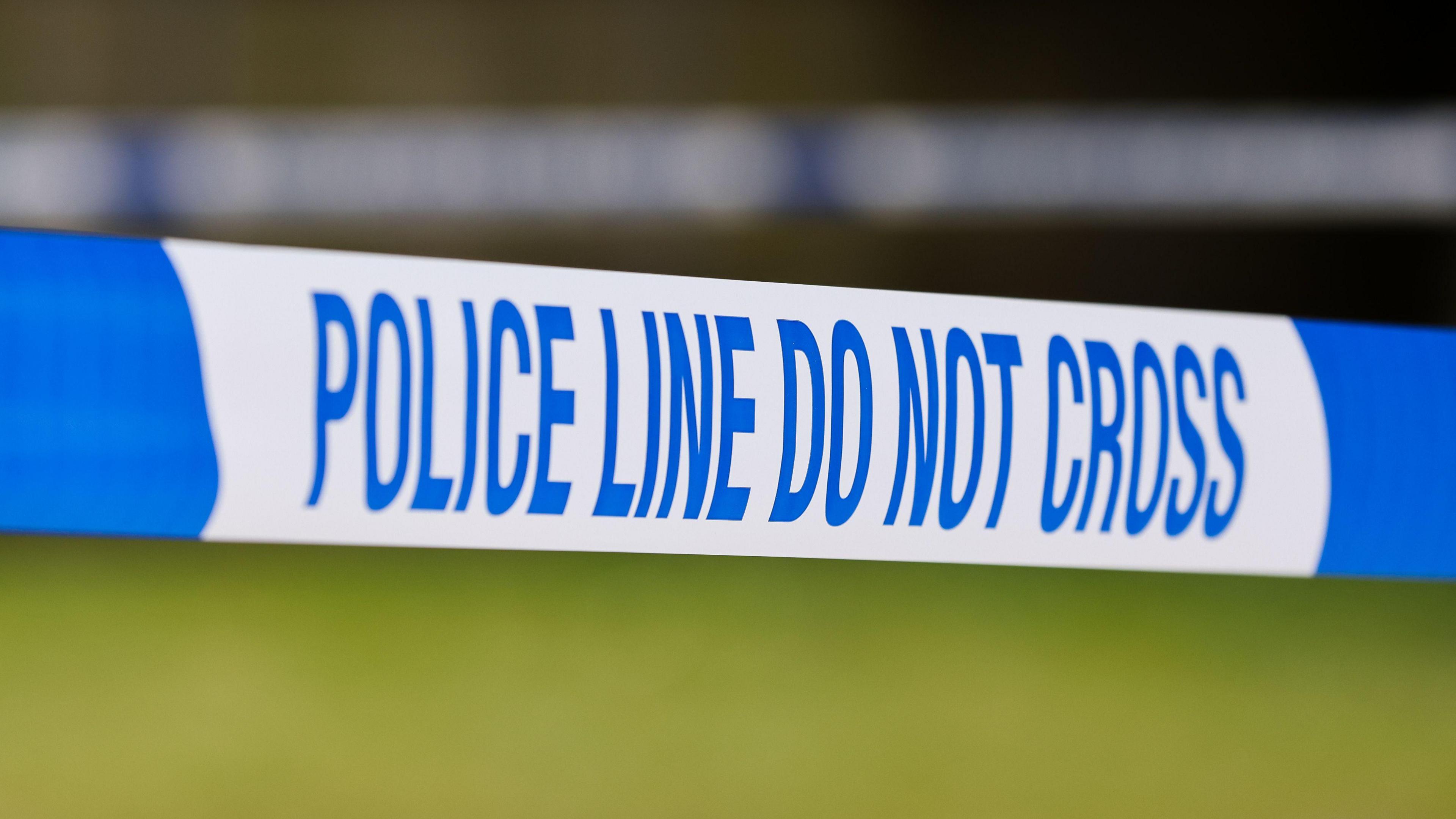 Blue and white police tape bearing the words: "Police line do not cross"