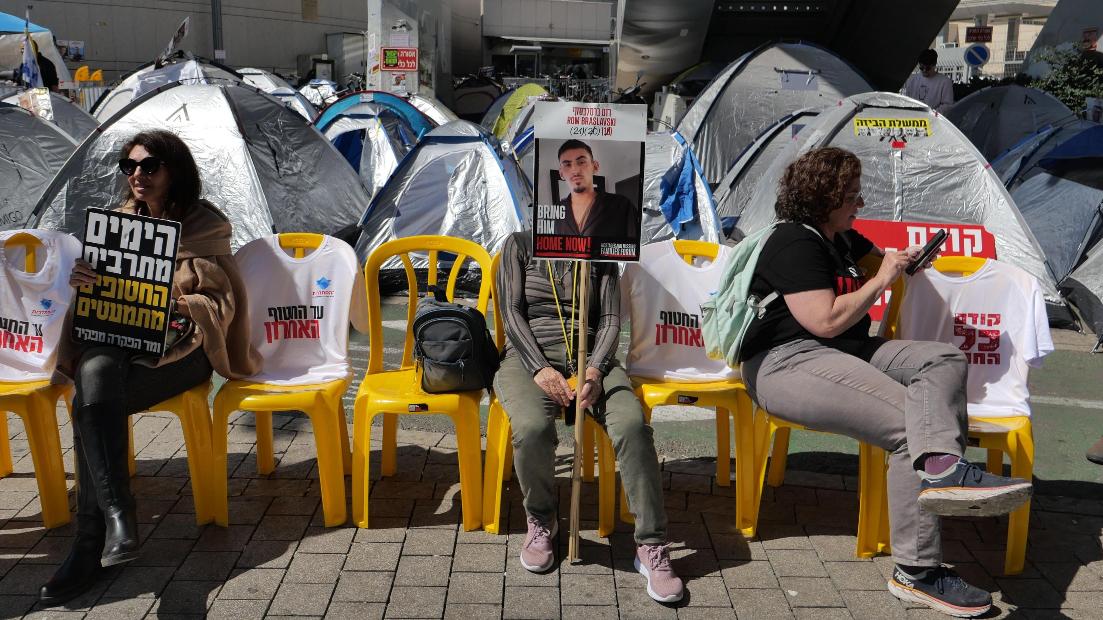 Israeli hostages' families and their supporters hold up photos posters calling for their release, as they sit next to tents near the Israeli defence ministry in Tel Aviv, Israel (11 March 2025)