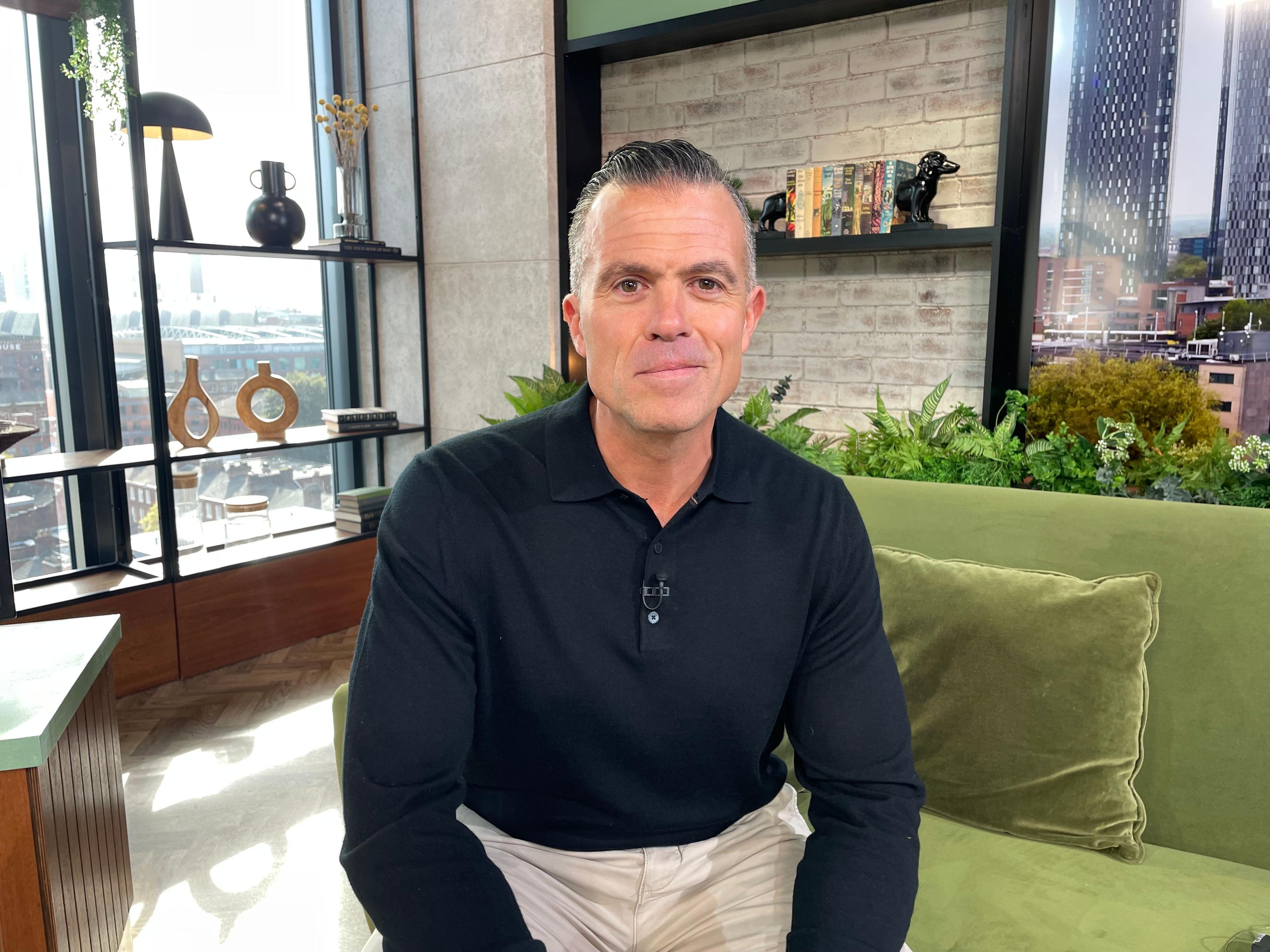 Former detective Marc Cananur sits in the Morning Live studio on the green velvet sofa, he wears a blue polo shirt and cream trousers.