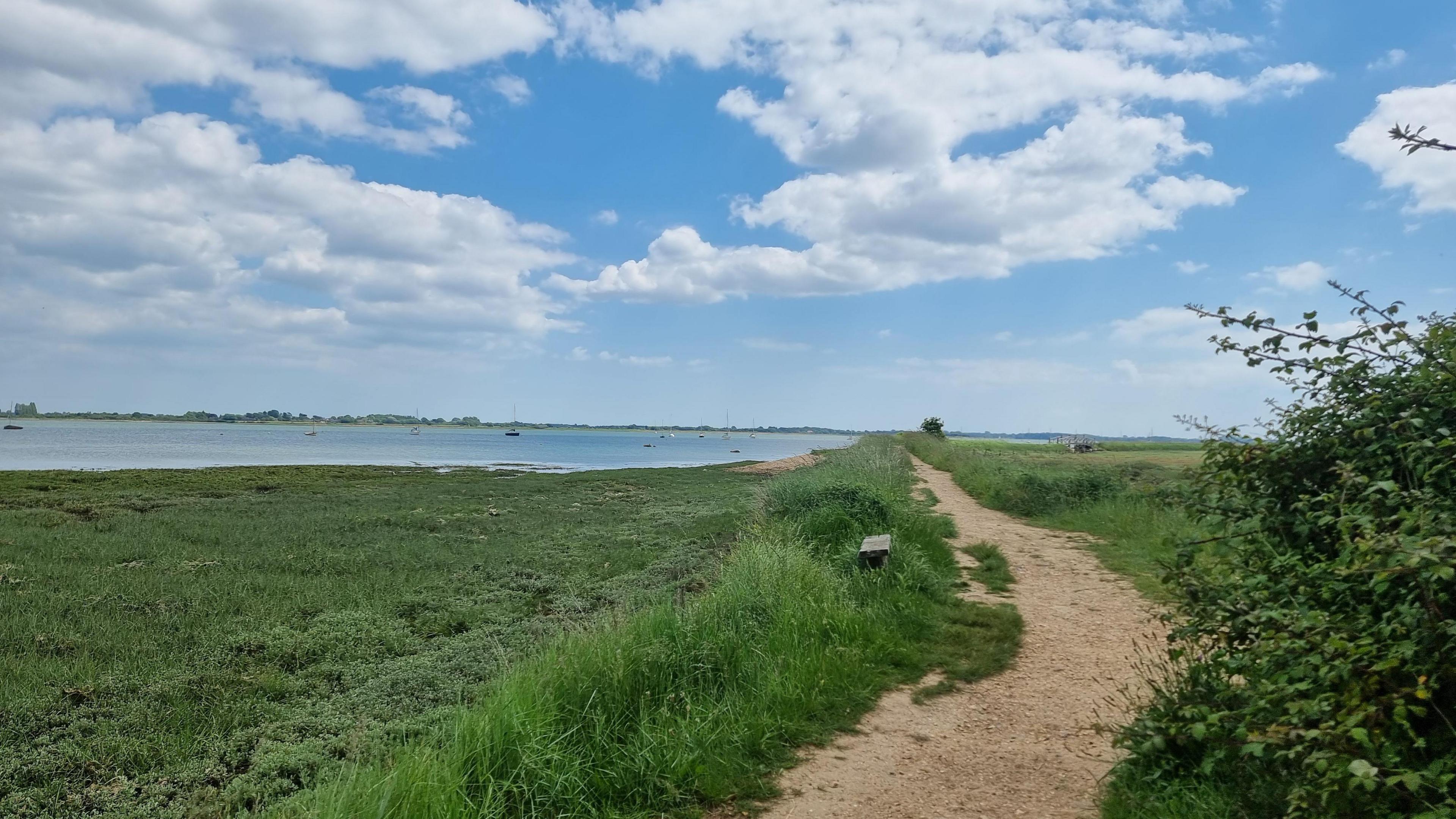 Thorney Island, a peninsula that juts into Chichester Harbour in West Sussex. The sea can be seen to the left of a walking path and grass.