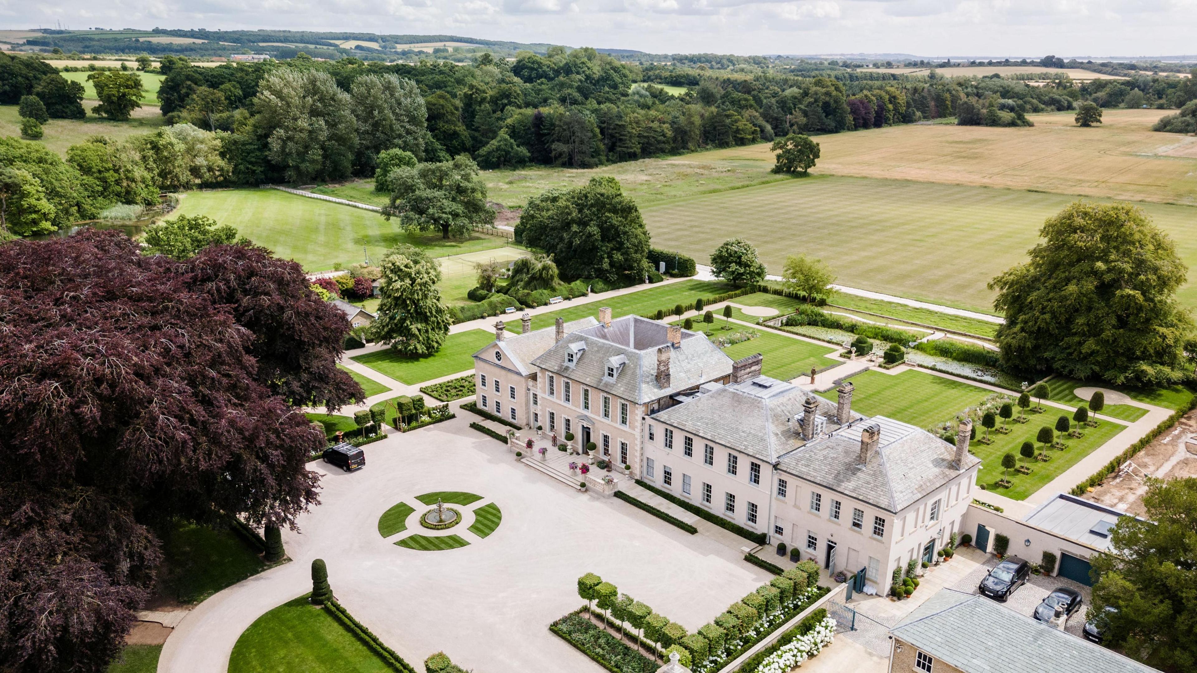 An aerial view of the Hotham Hall estate with the main driveway, house and landscaped gardens.