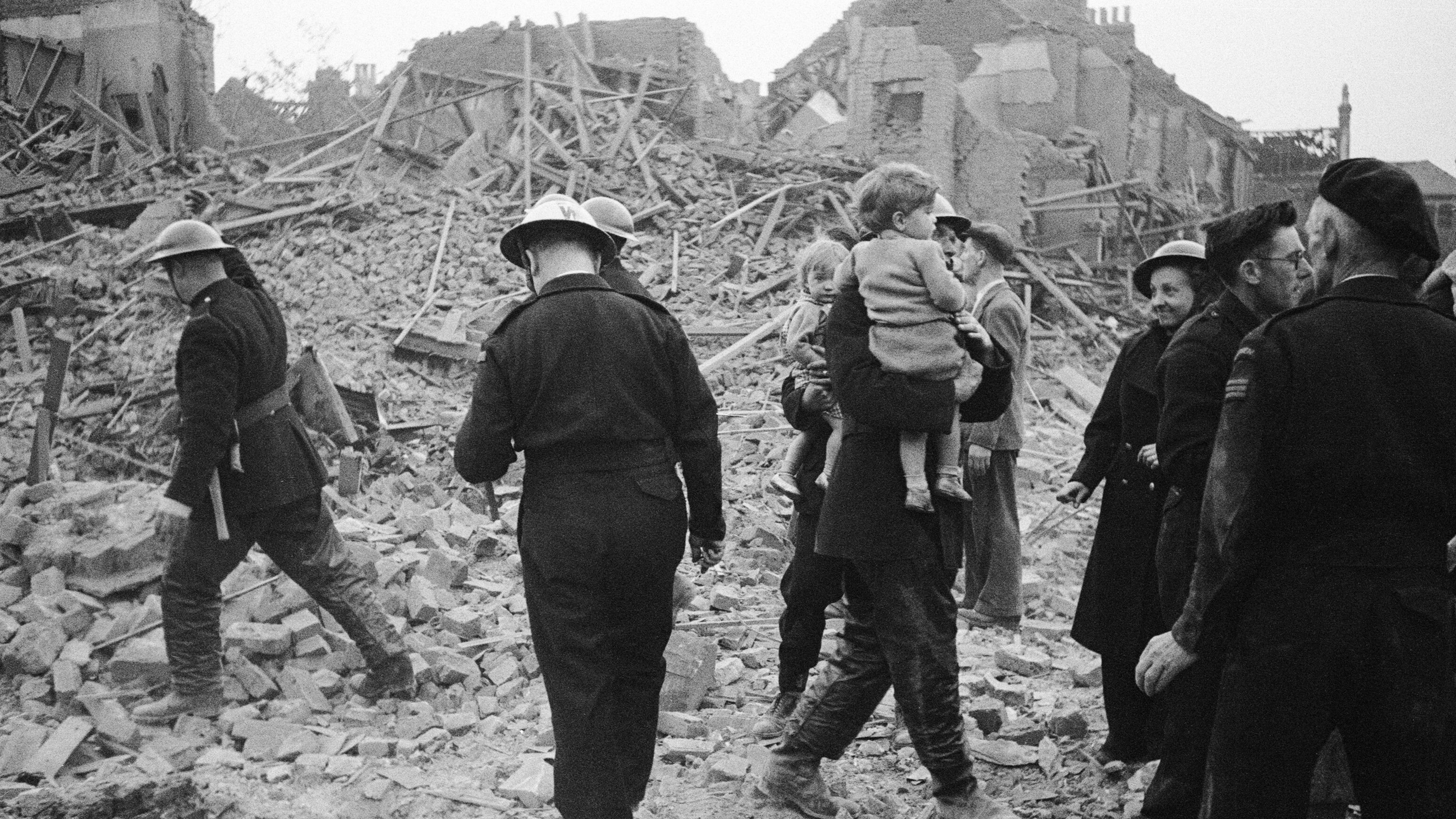 Firemen carrying young children through the ruins of a house.