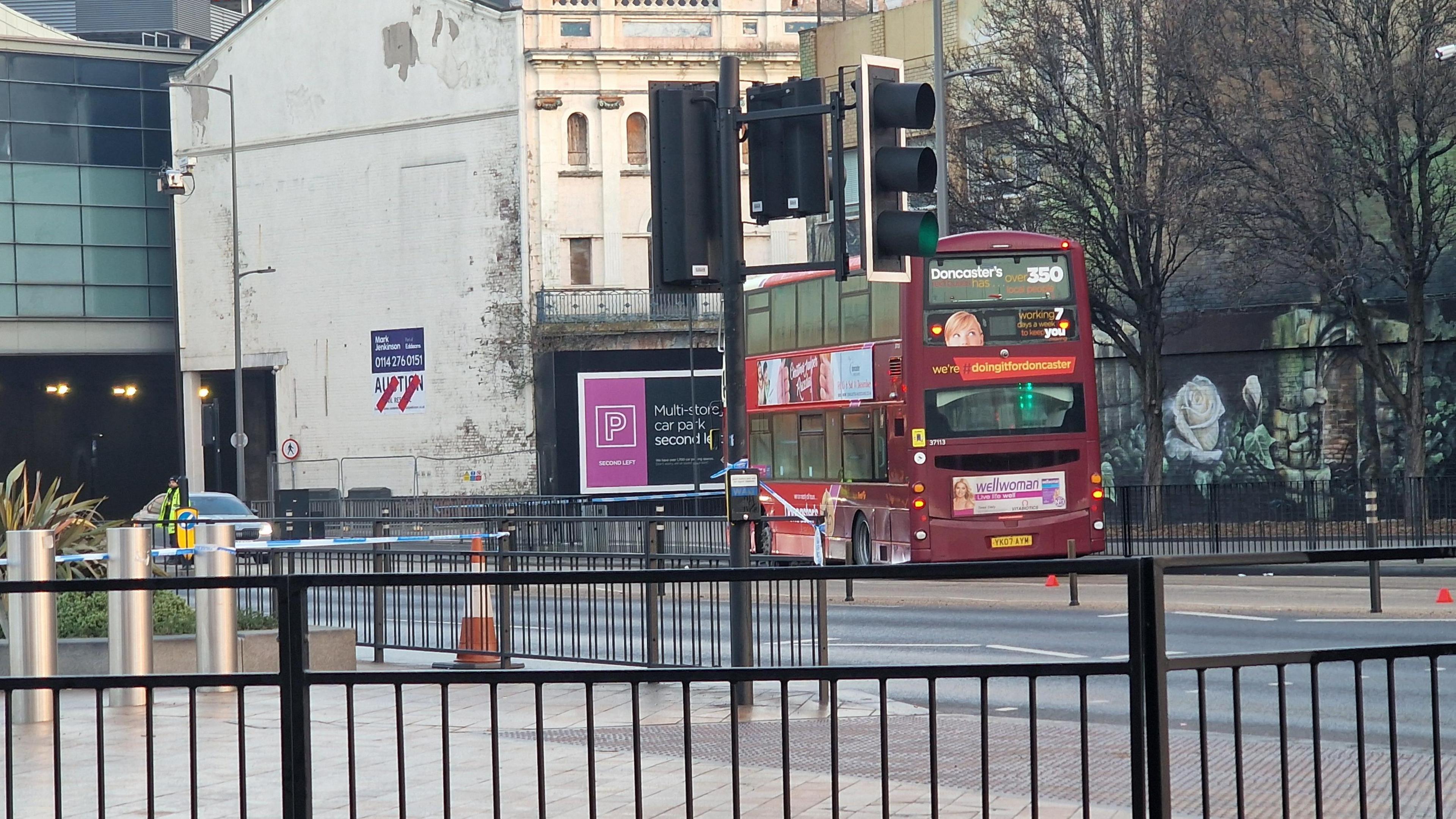 The bus, pictured from behind a set of traffic lights. A police cordon can be seen close by.