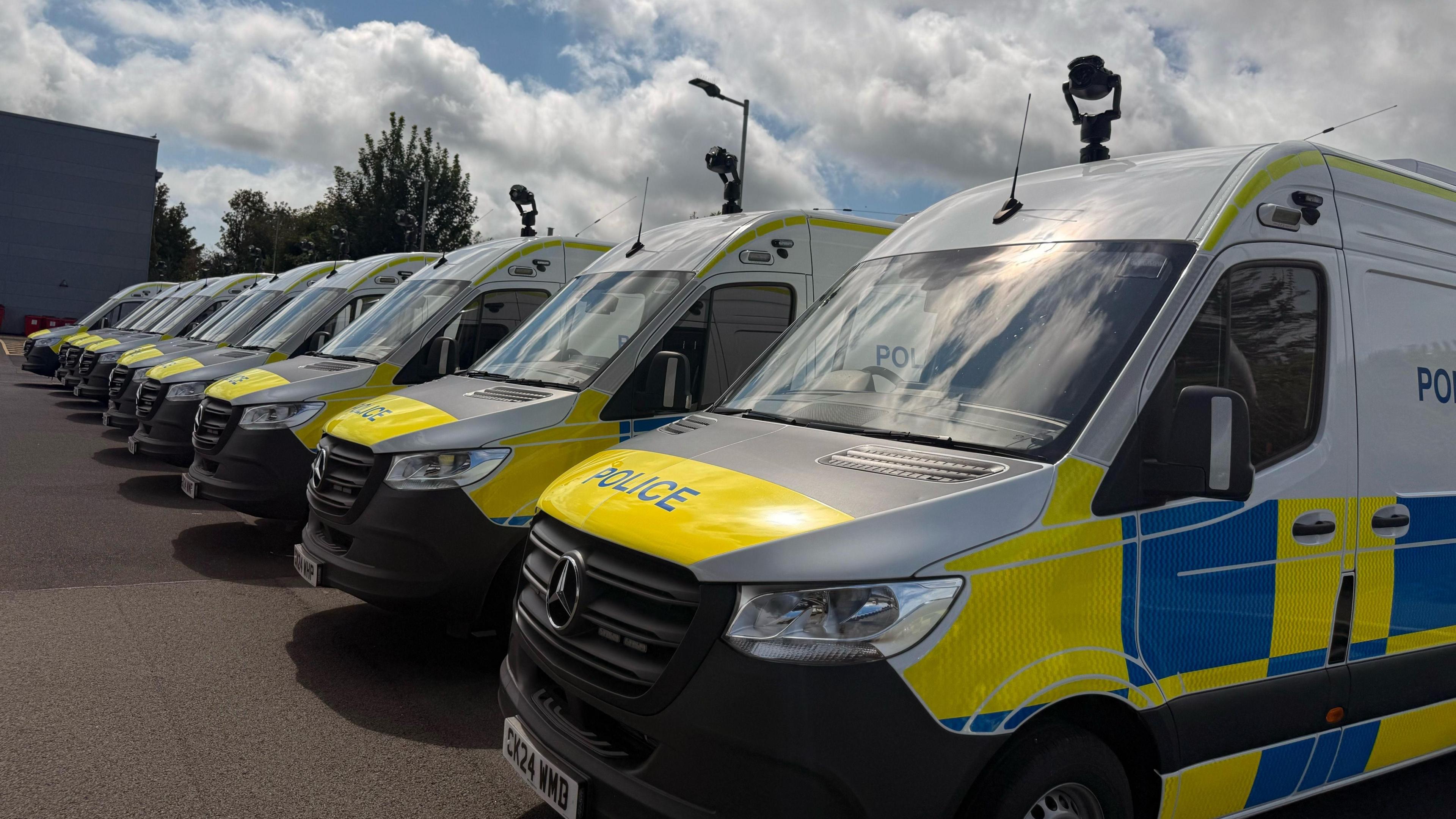 Nine police vans lined up with cameras attached to the top