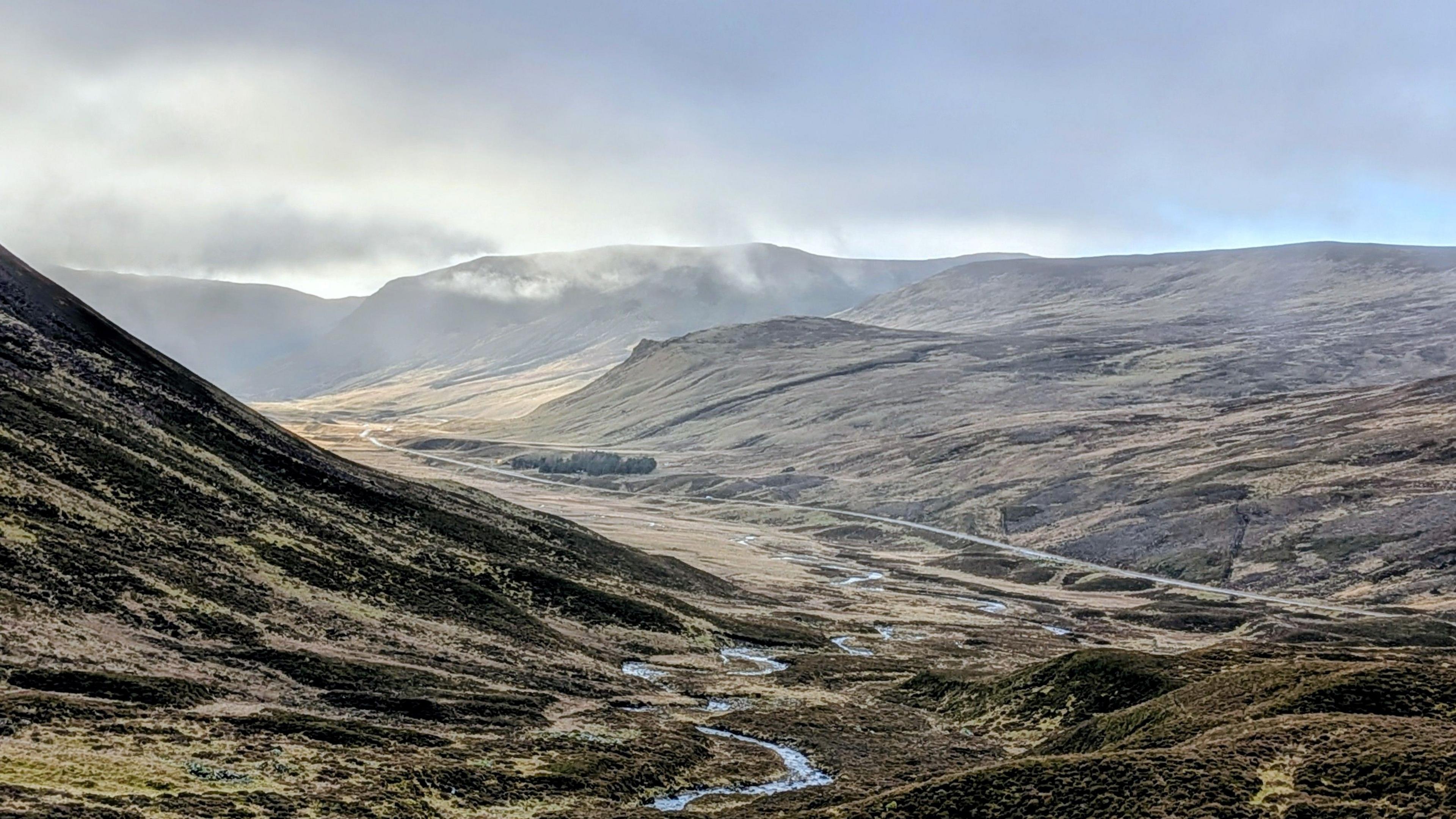 Mountains and rolling hills, with sunshine and mist above them 