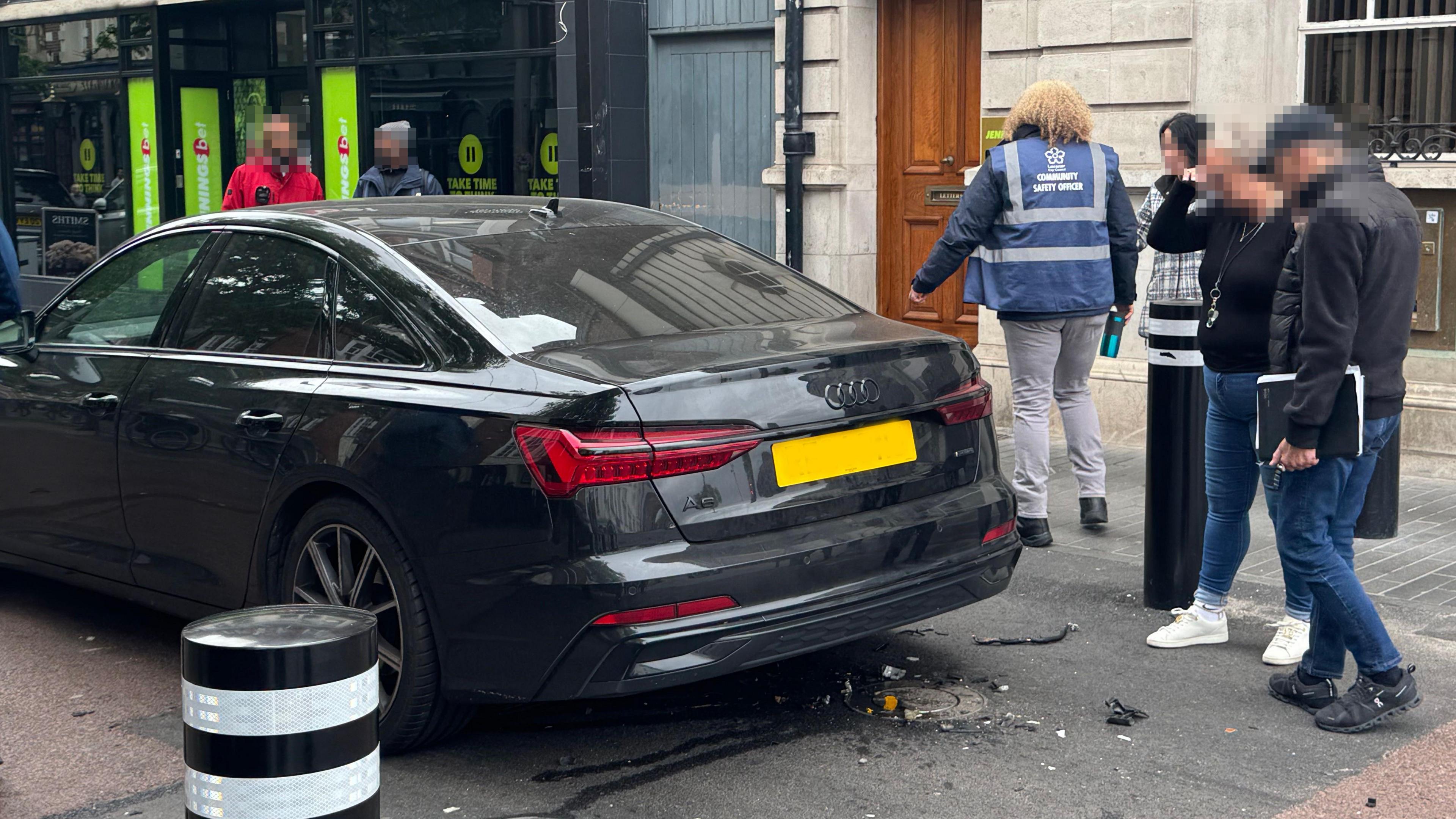 The back of a car hit by a rising bollard, with debris left on the road.