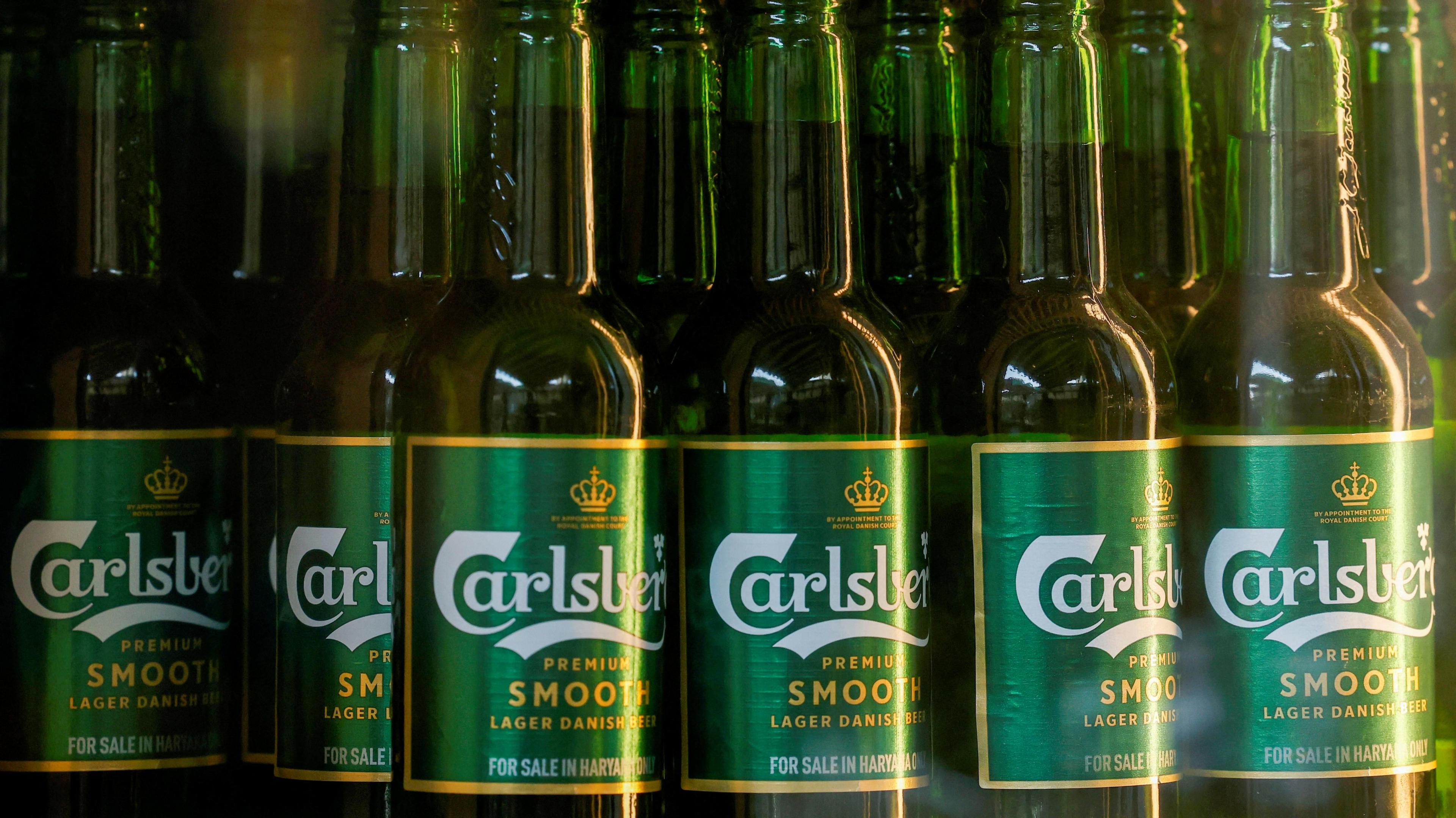 A close-up of a row of bottles of Carlsberg beer tightly packed together.